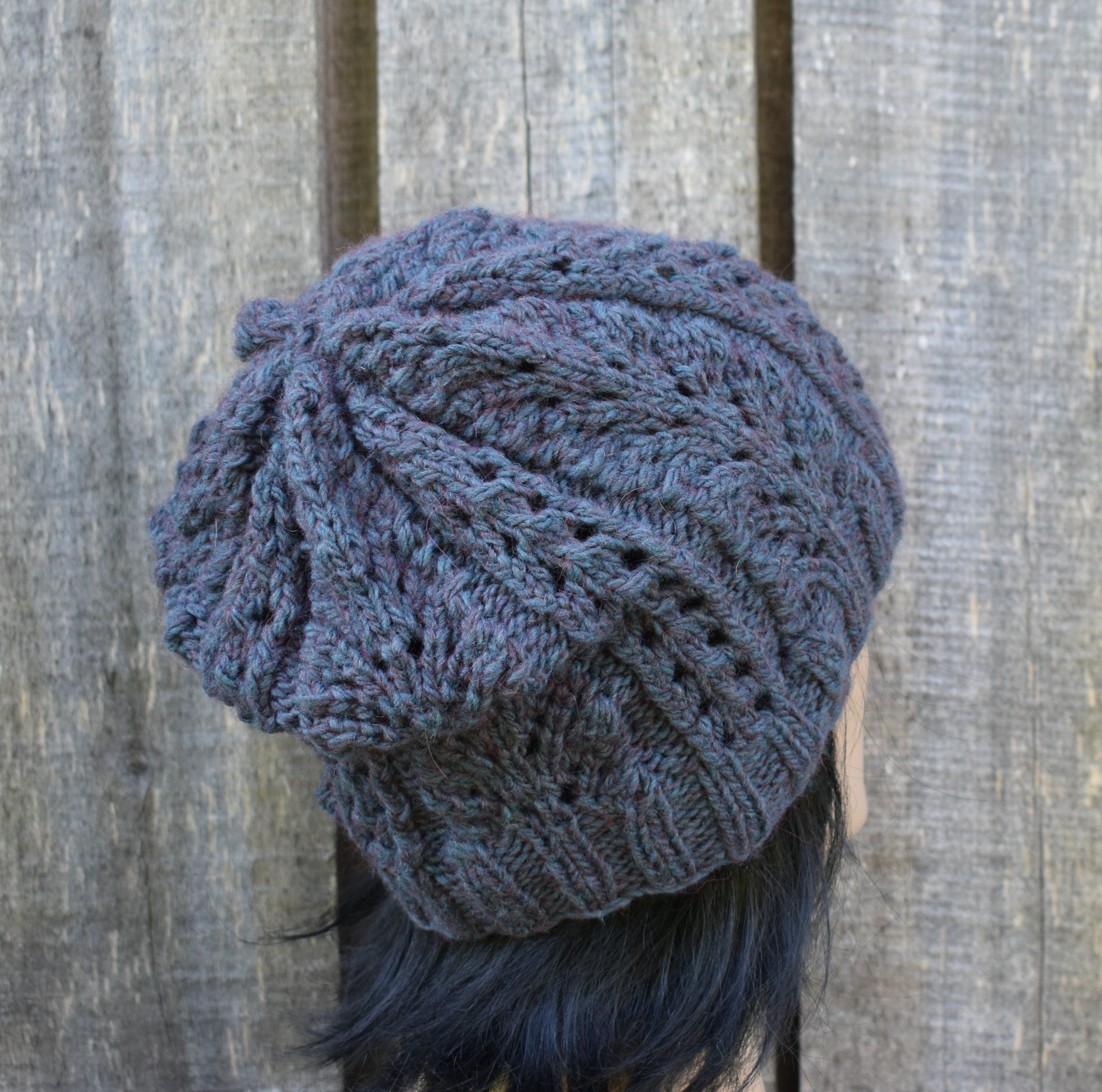 Blue knitted beanie on a person against a wooden background