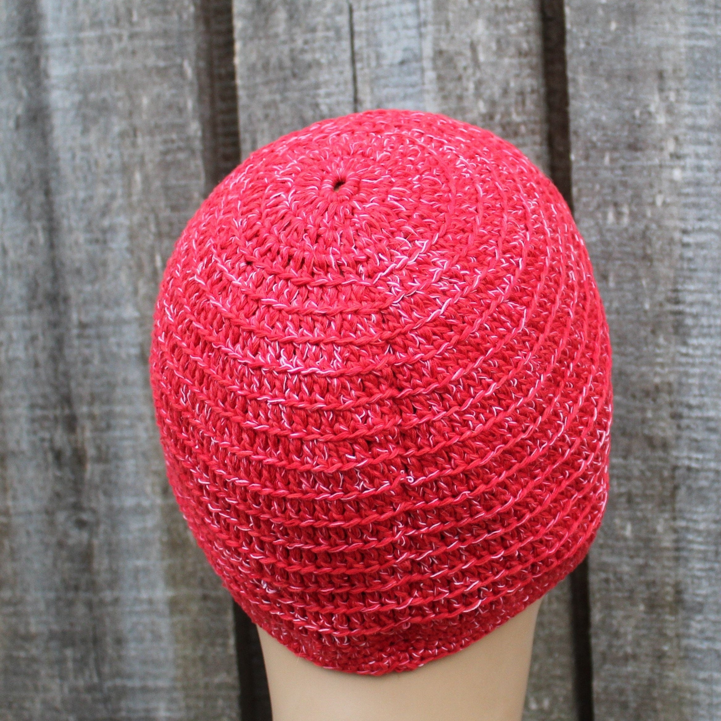 Red knitted beanie on a mannequin head against a wooden background