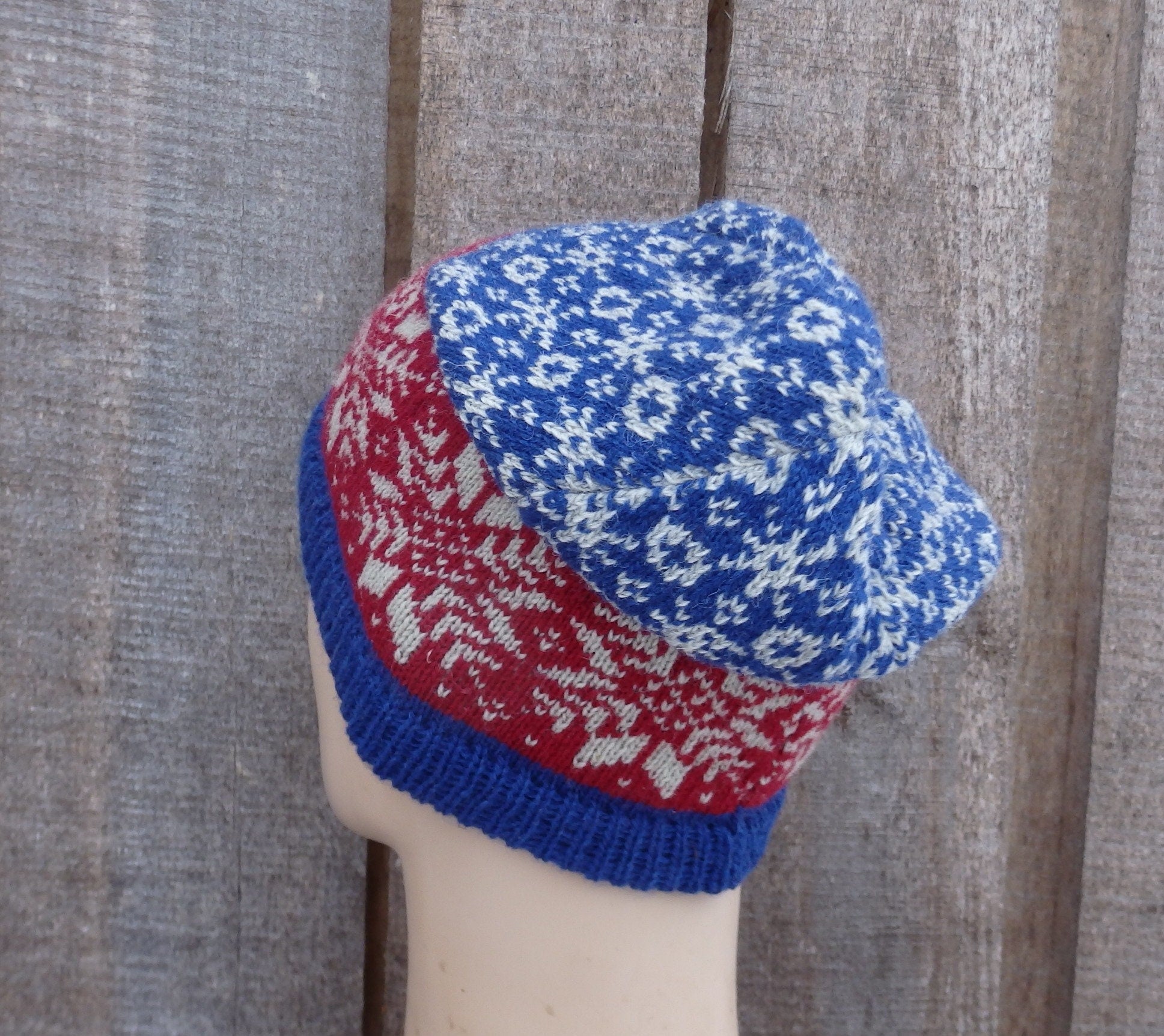 Knitted hat with red, blue, and white pattern on a wooden background