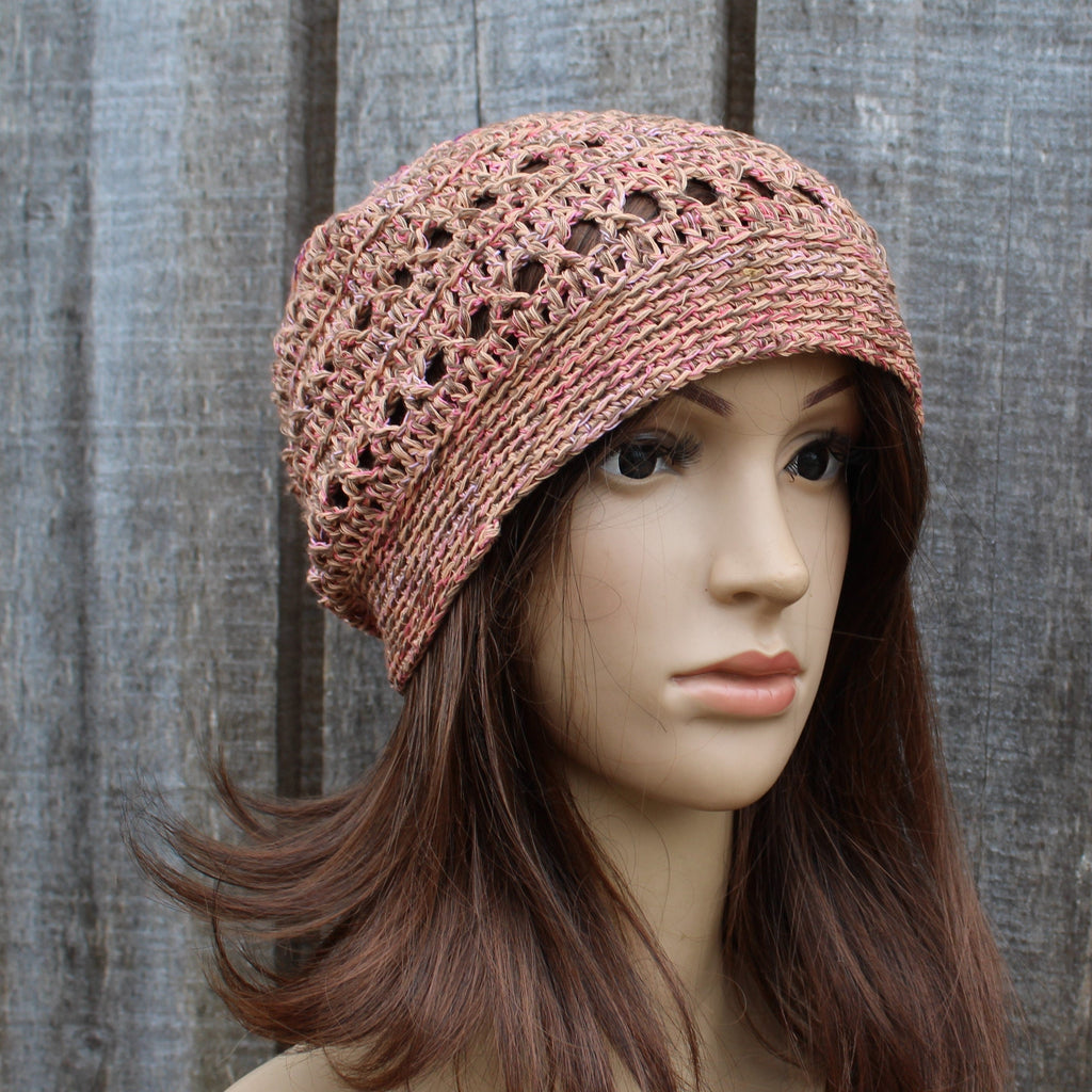 Mannequin head wearing a orange brown crochet hat against a wooden background