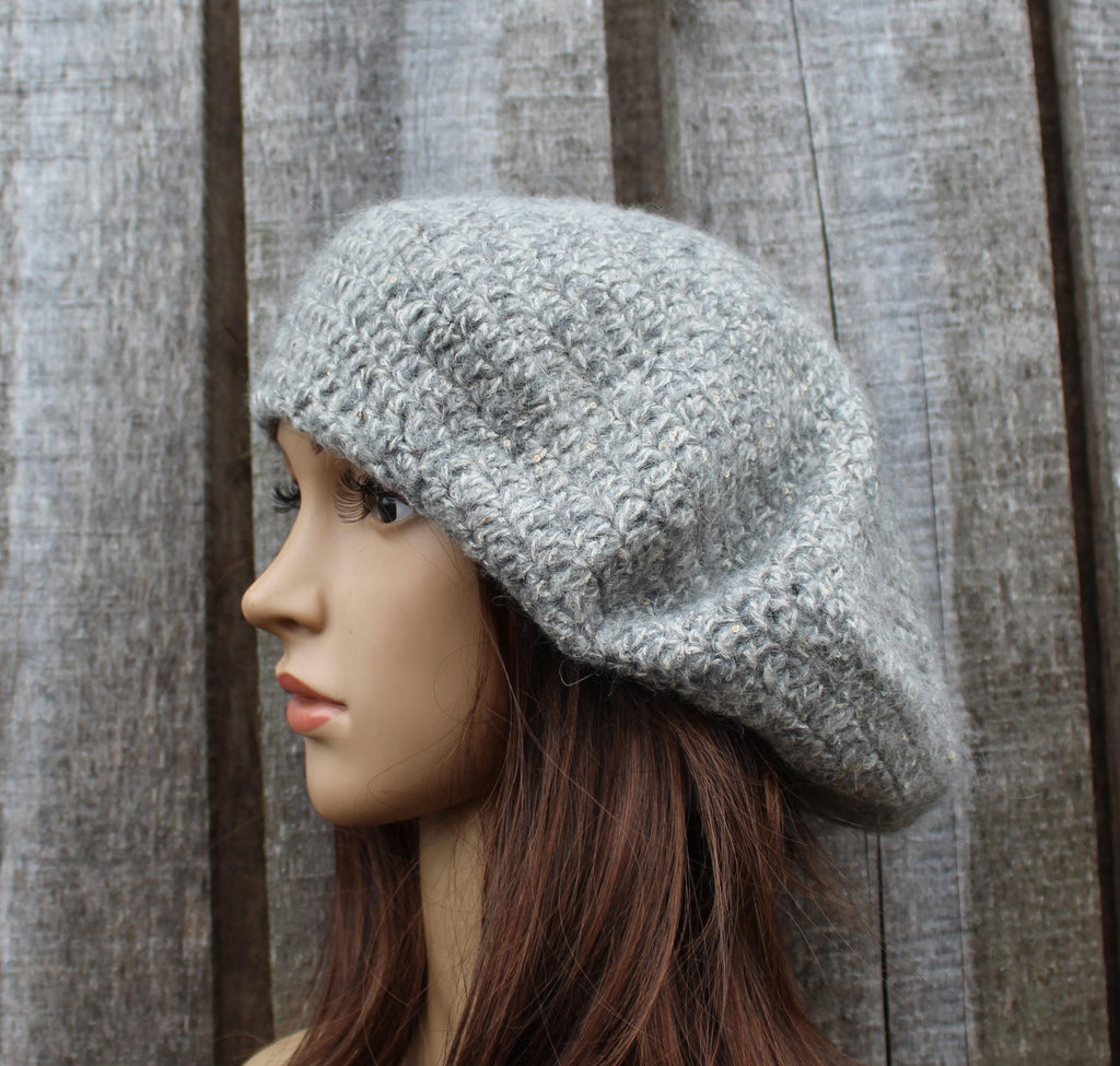Mannequin head wearing a textured gray knit hat against a wooden background