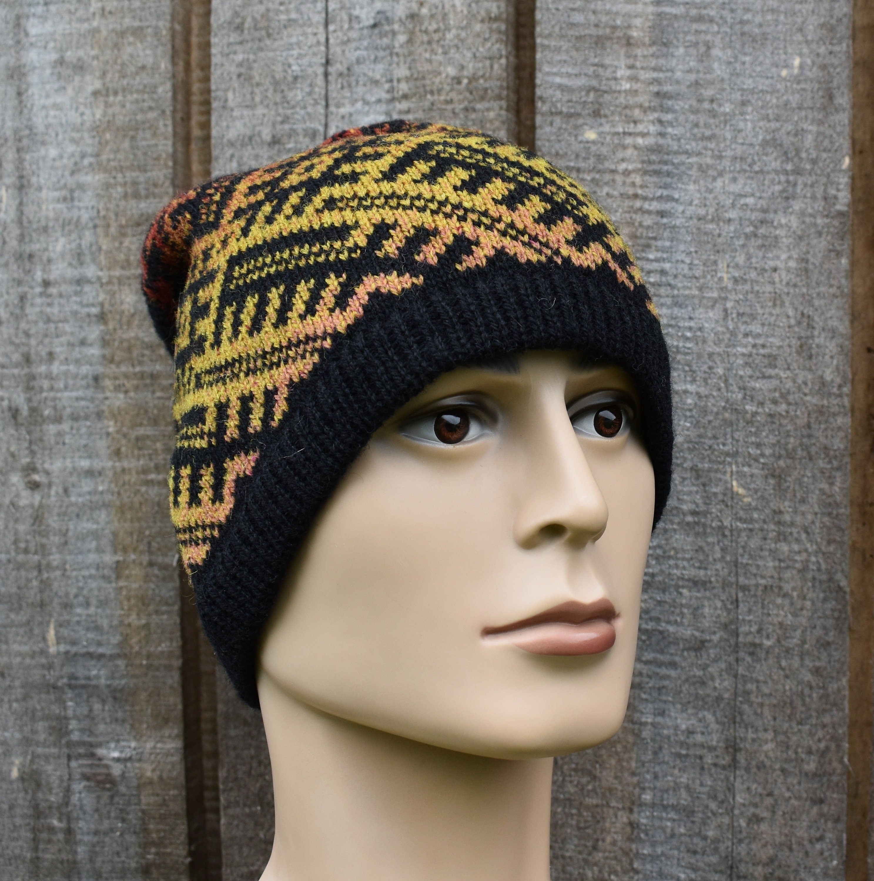 Knitted hat with a geometric pattern on a mannequin head against a wooden background