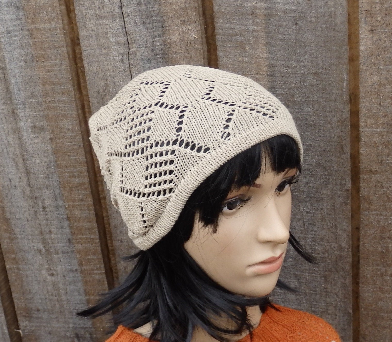 Mannequin head wearing a beige knitted hat against a wooden background