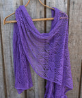 Purple knitted shawl on a wooden hanger against a wooden background