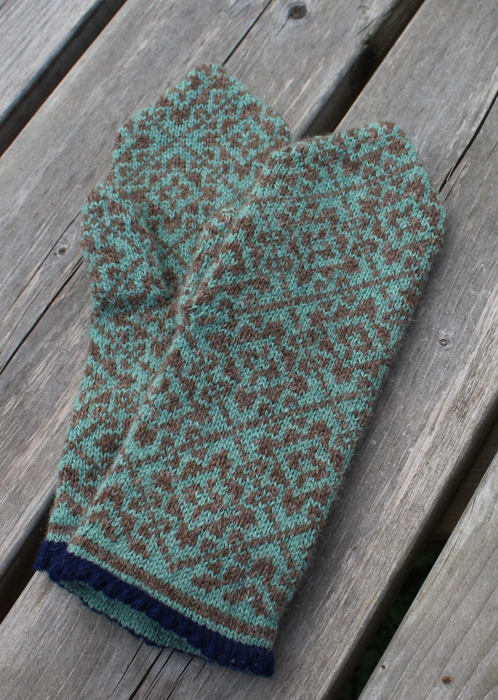 Knitted mitten with a pattern on a wooden surface