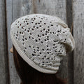 Knitted beige hat worn by a person against a wooden background