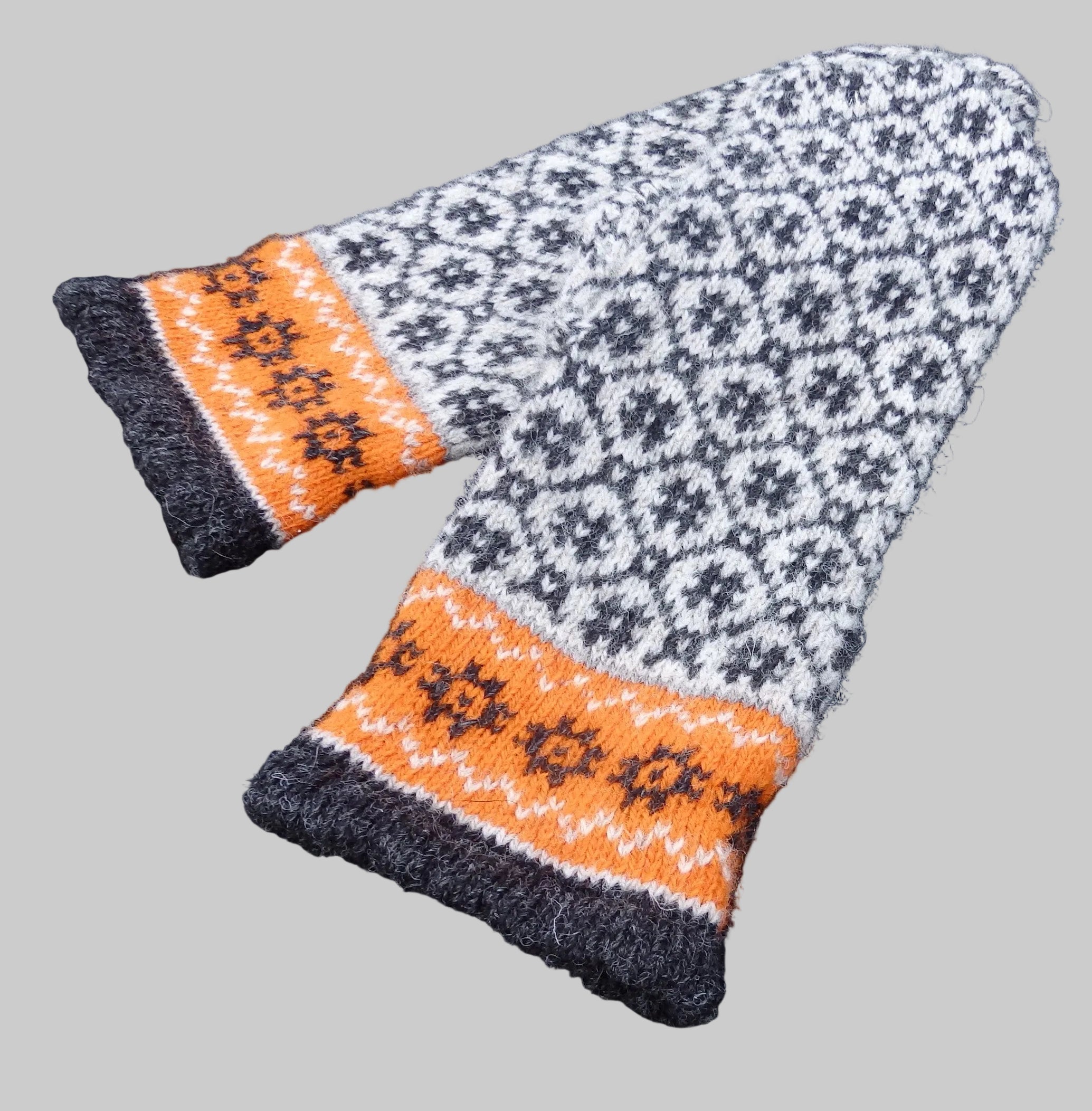 Knitted hat and mitten set with orange and gray pattern on a dark background
