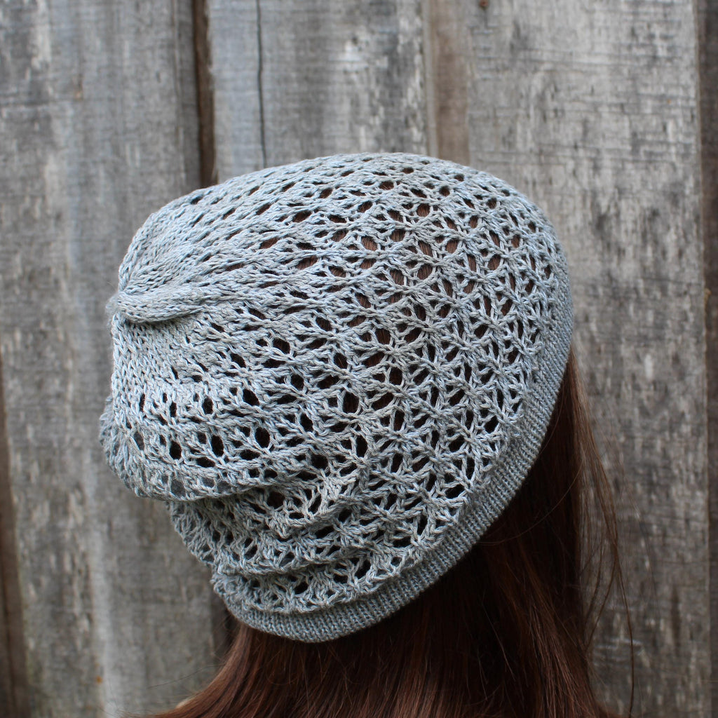 Light gray knitted beanie worn by a person against a wooden background