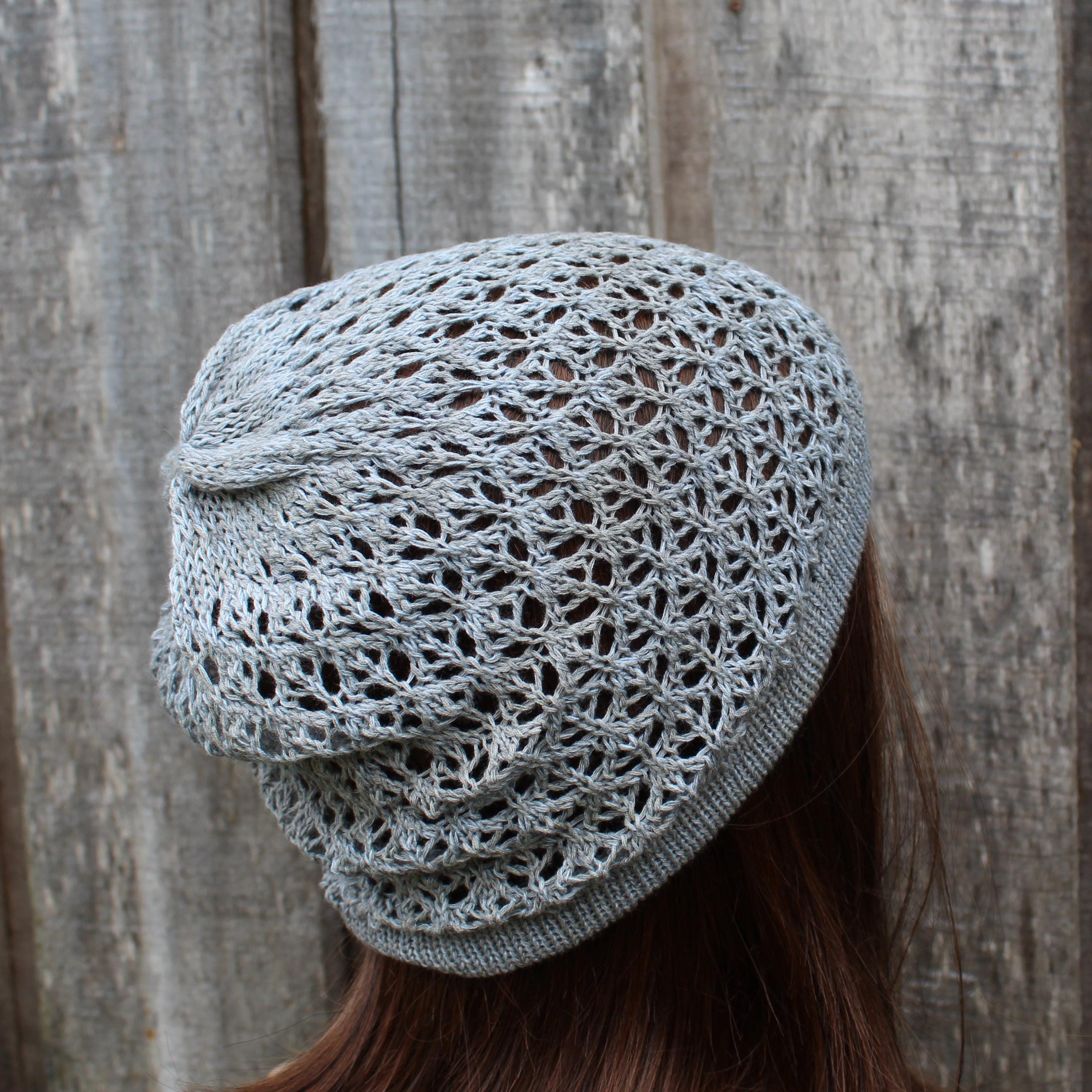 Light gray knitted beanie worn by a person against a wooden background