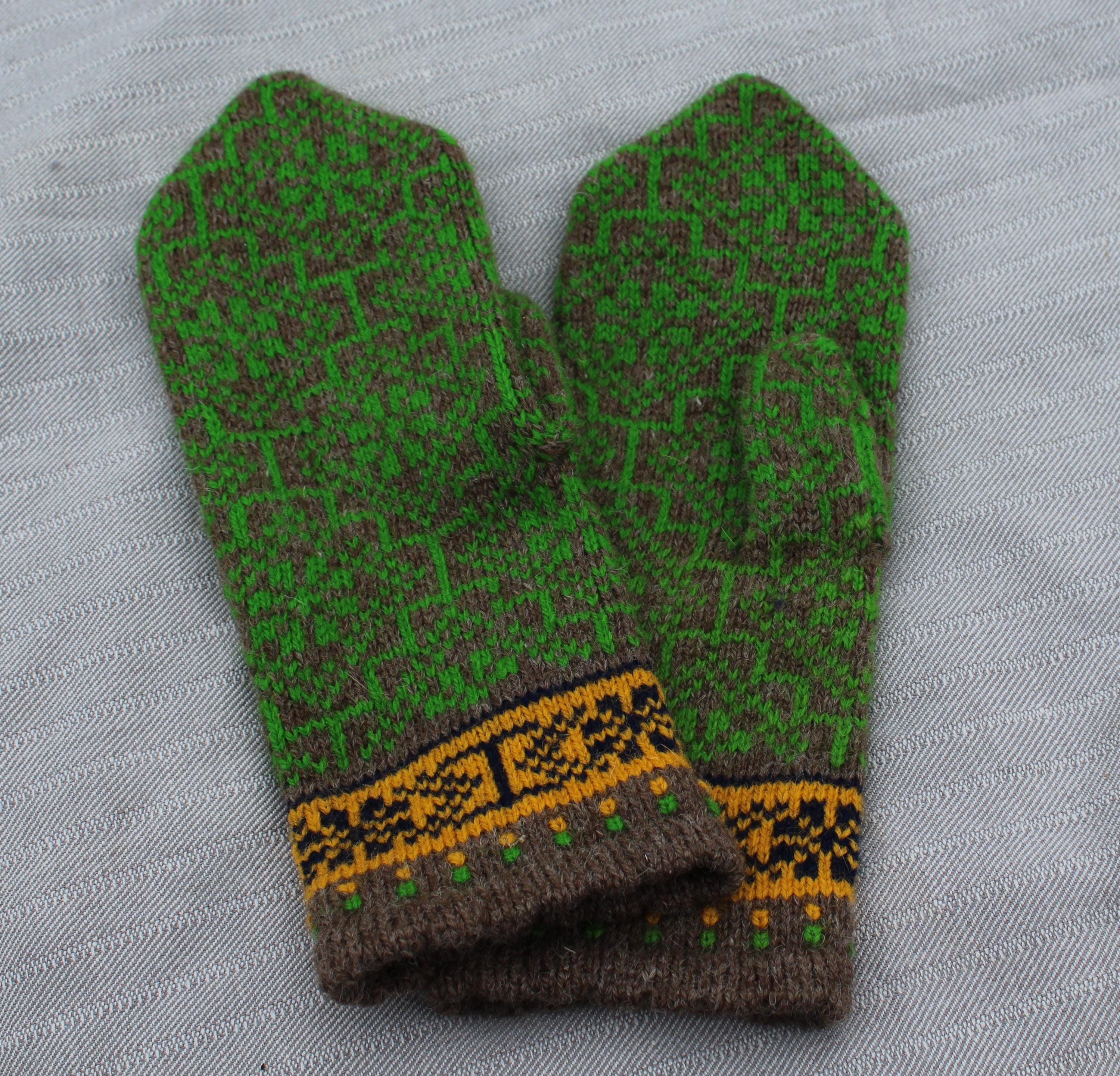 Pair of green and brown knitted mittens with a decorative band on a light gray background