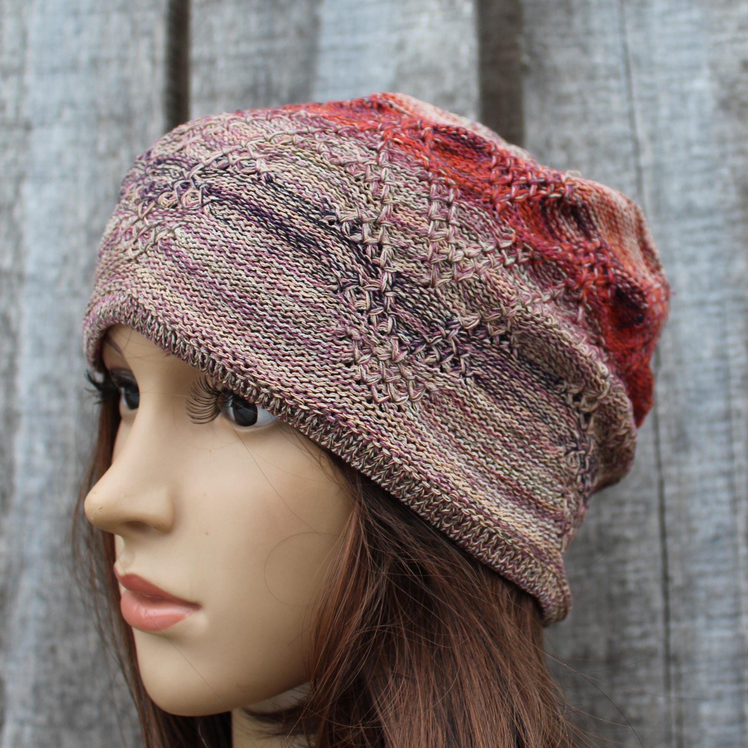 Knitted multicolored beanie on a mannequin head against a textured gray background