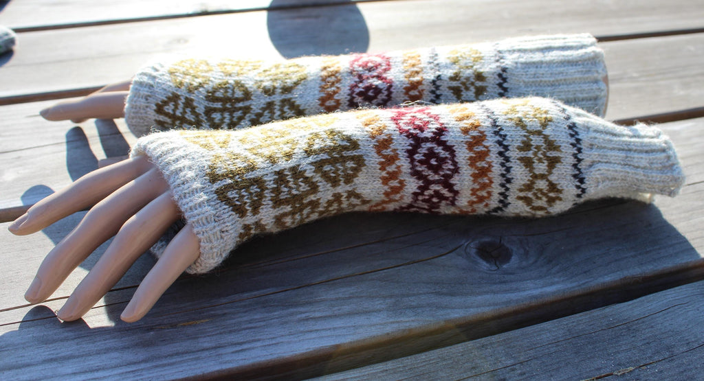 Pair of knitted arm warmers with a pattern on a wooden surface