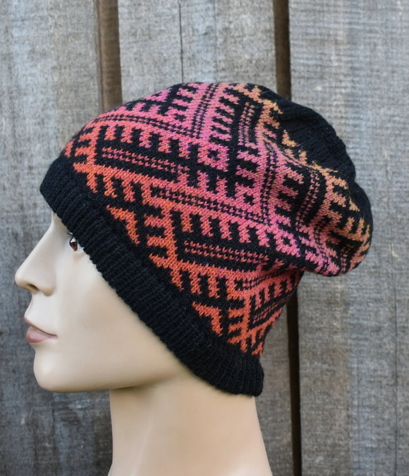 Knitted beanie with a geometric pattern on a mannequin head against a wooden background