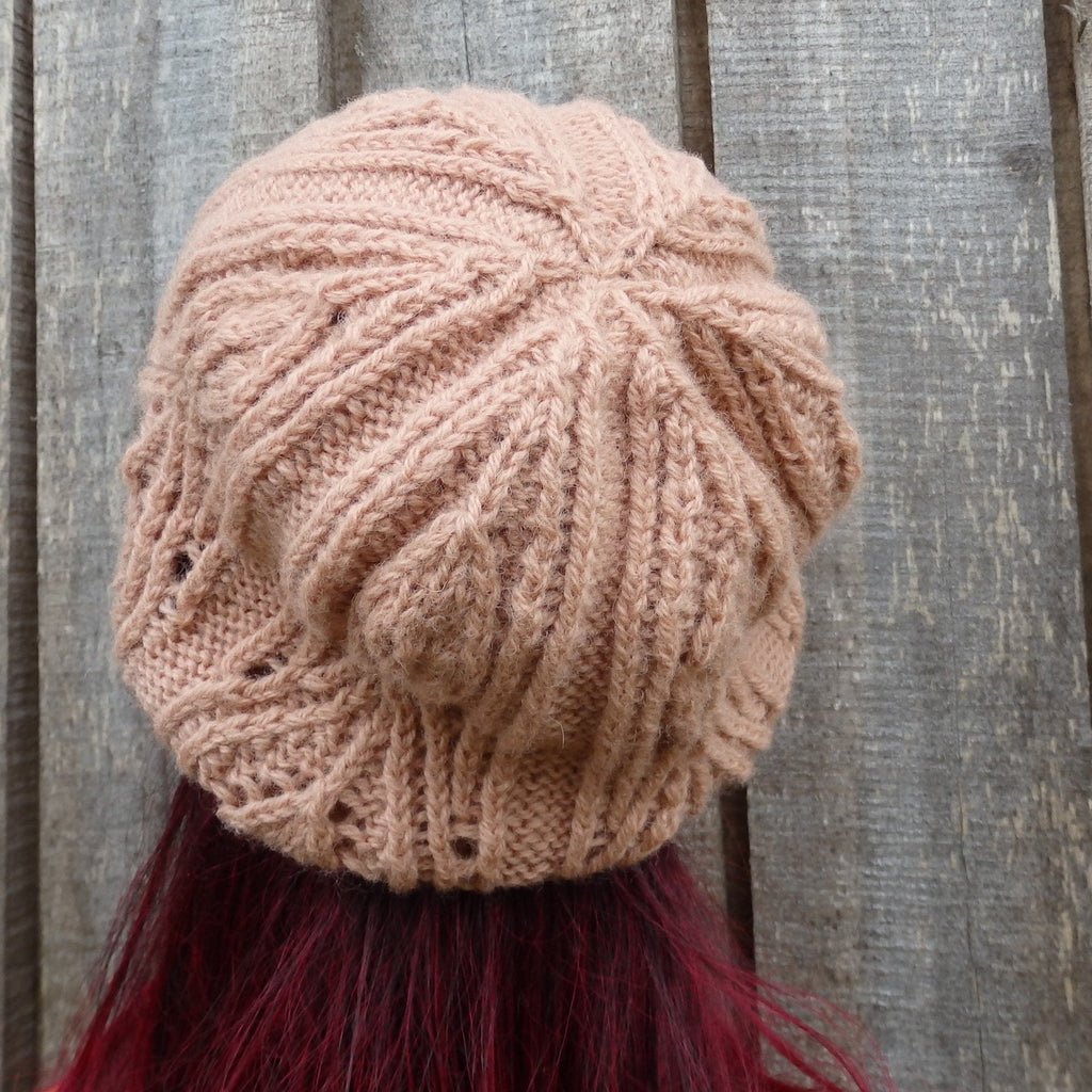 Knitted beige beanie on a person with red hair against a wooden background