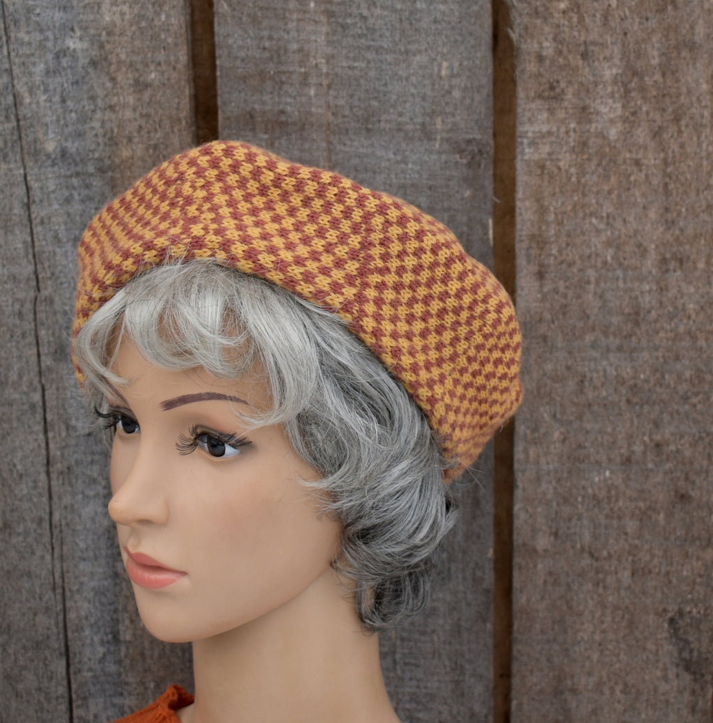 Mannequin head wearing a houndstooth patterned hat against a wooden background