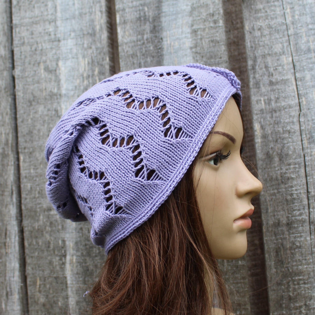 Mannequin head wearing a purple knitted hat against a wooden background