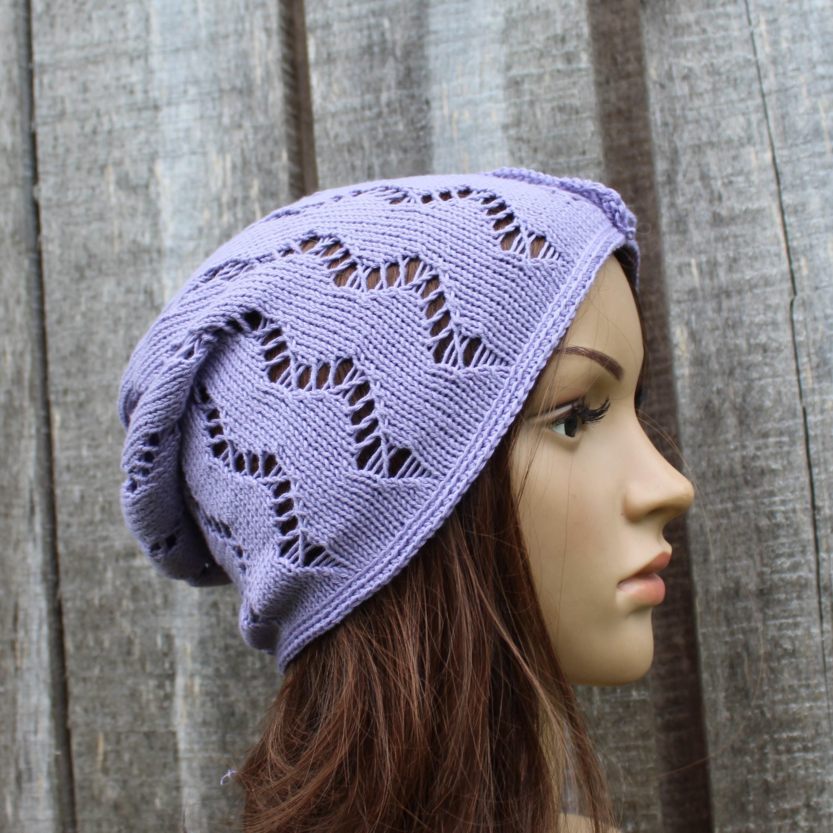 Mannequin head wearing a purple knitted hat against a wooden background