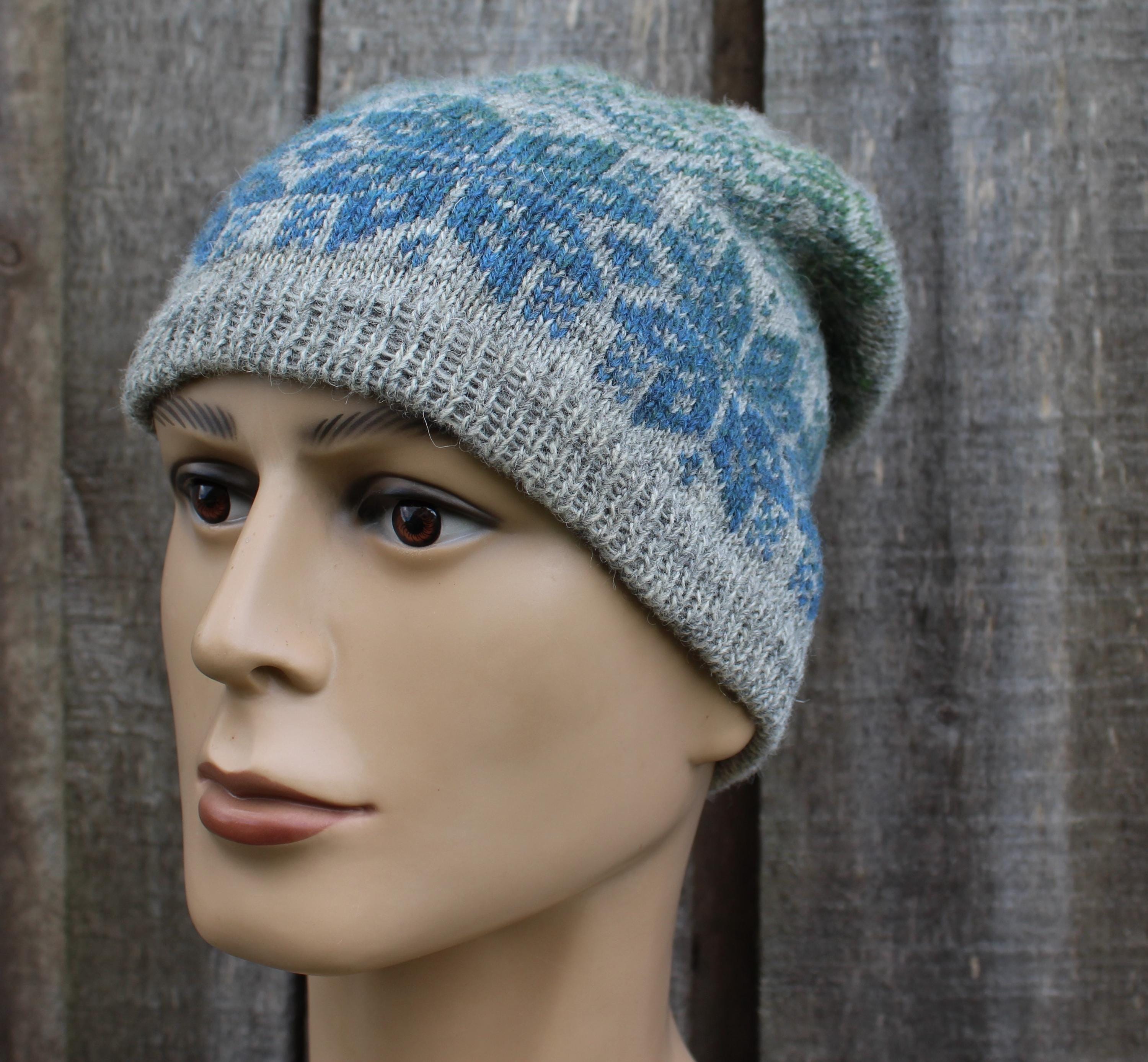 Knitted hat with blue and green pattern on a mannequin head against a wooden background