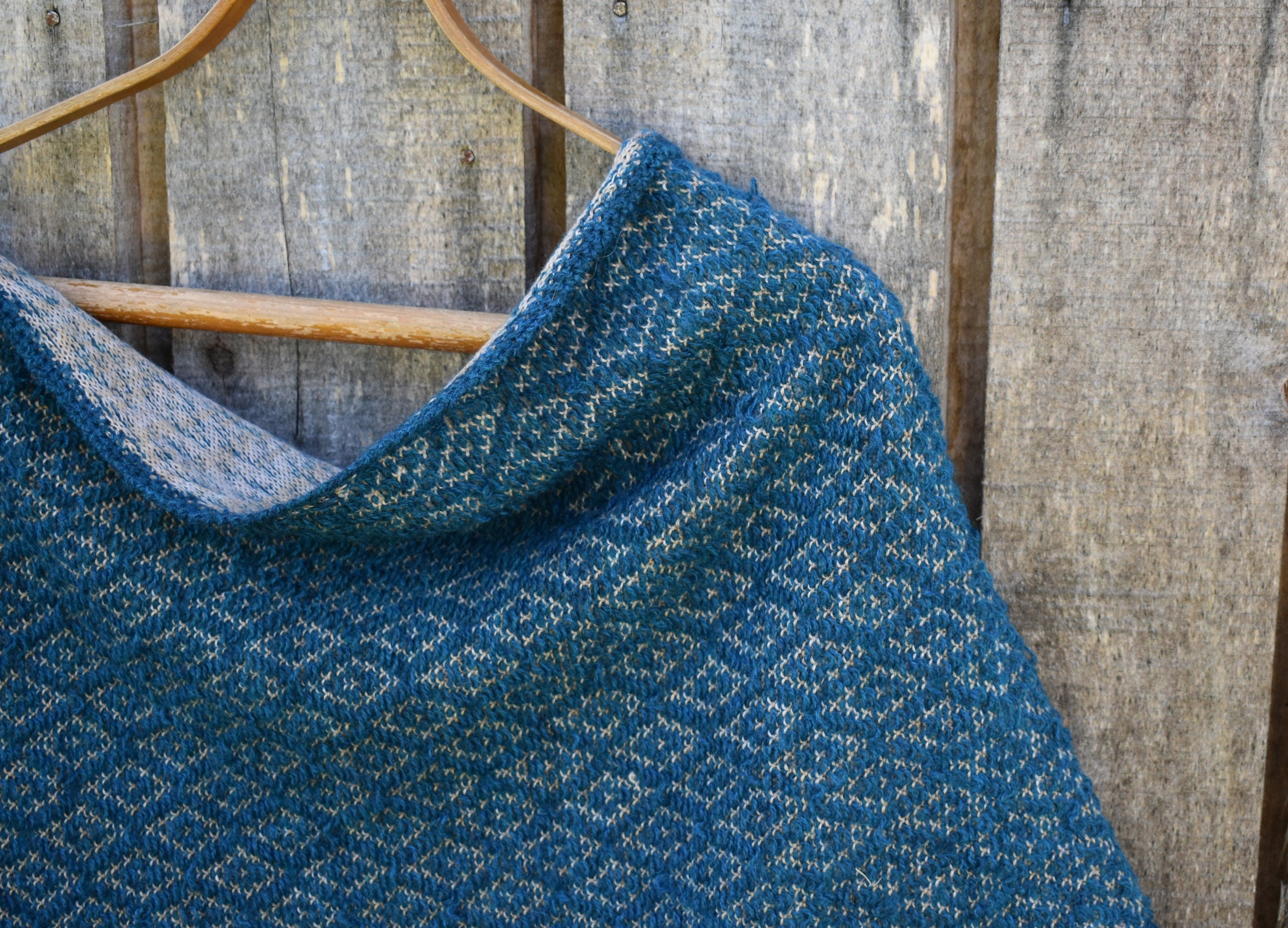 Blue textured fabric draped over a wooden hanger against a wooden background