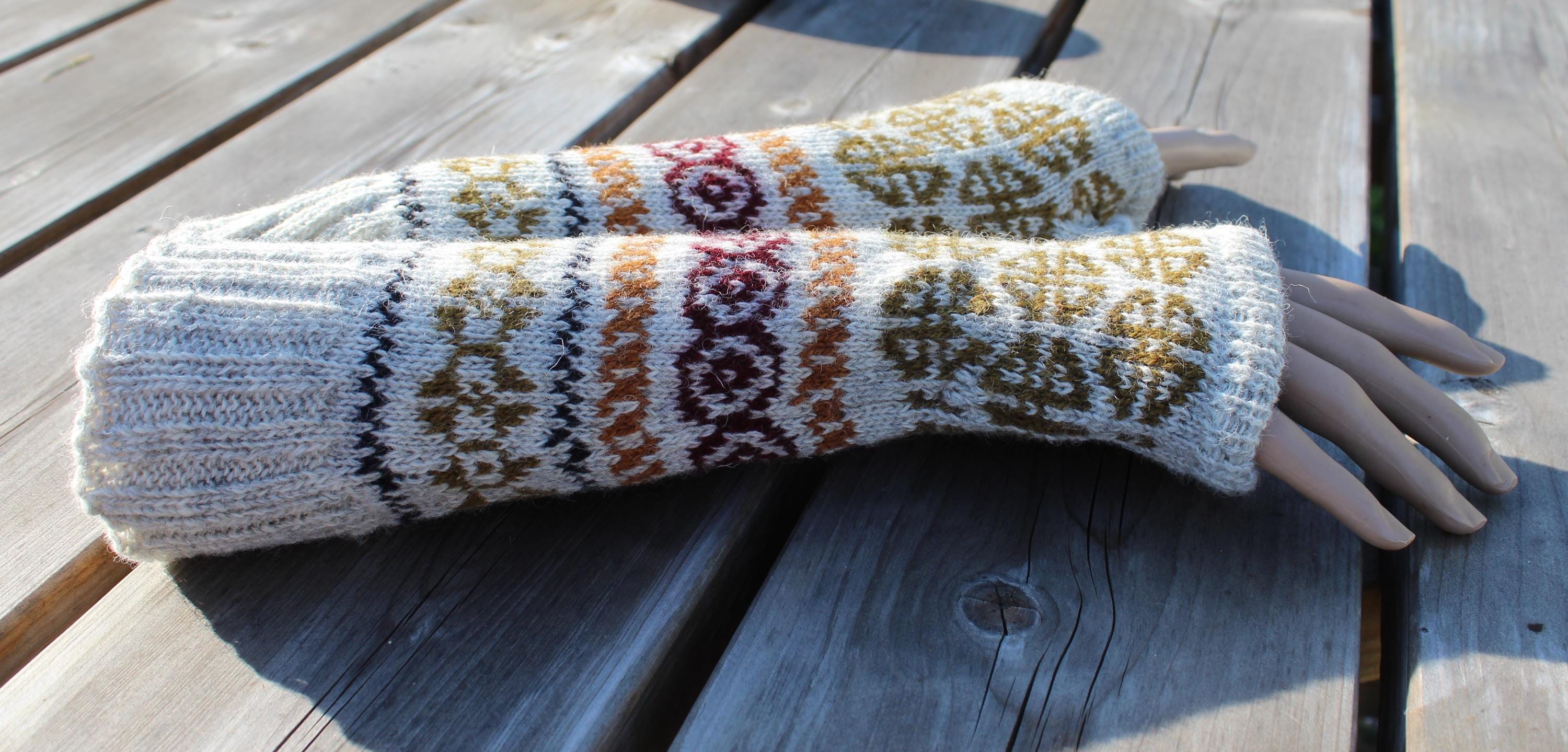 Pair of knitted arm warmers with a pattern on a wooden surface
