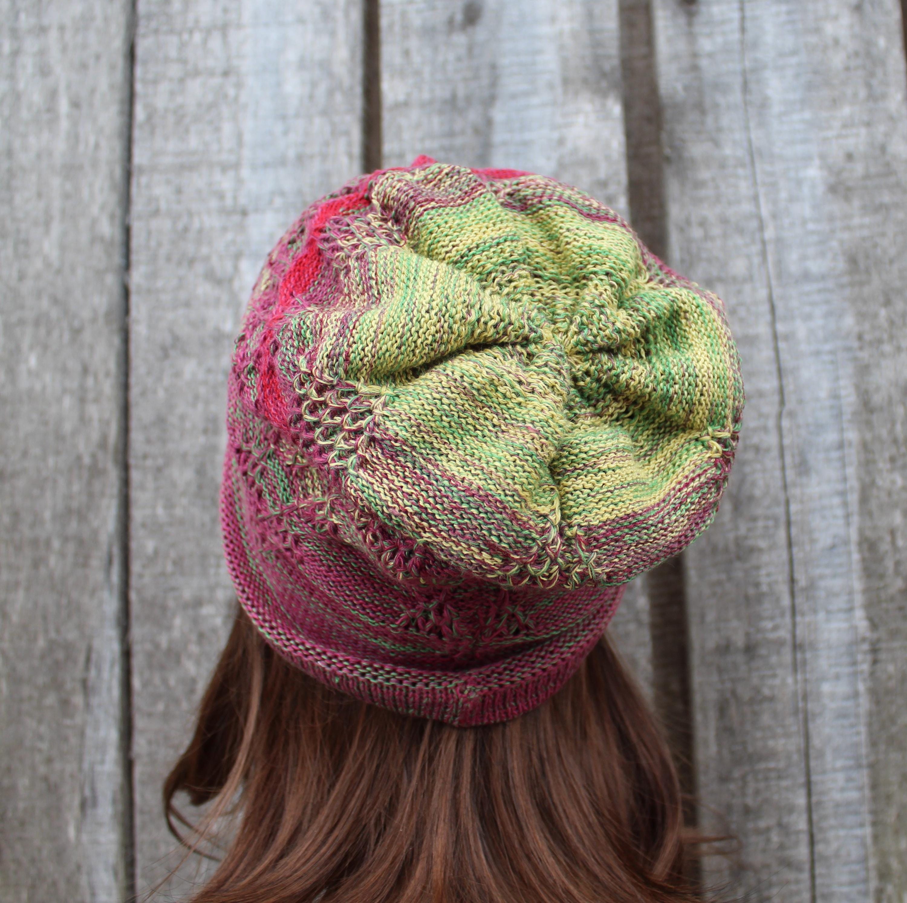 Knitted hat with pink and green pattern worn by a person against a wooden background