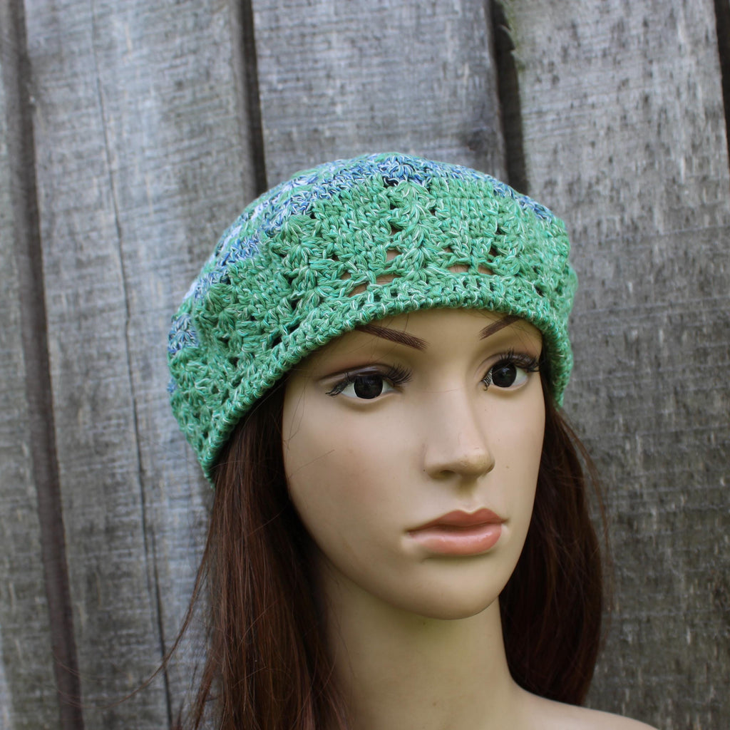 Green crocheted beanie on a mannequin head against a wooden background