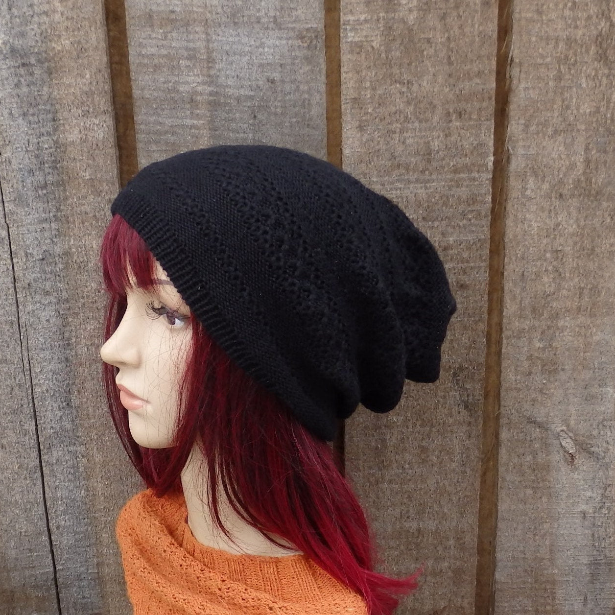 Mannequin head wearing a black knit beanie against a wooden background