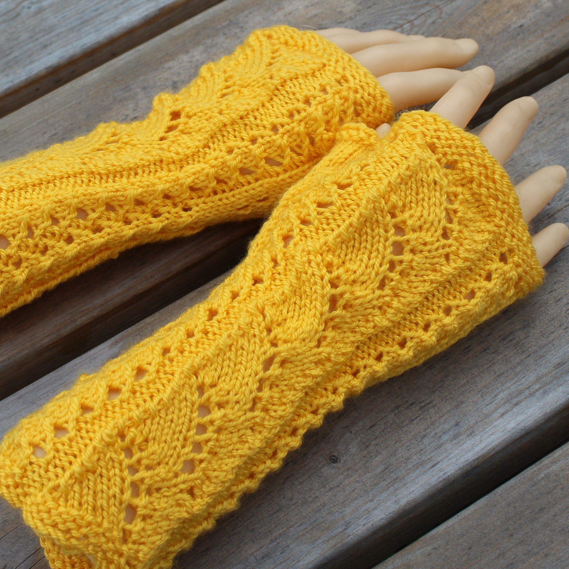 Yellow knitted arm warmers on a wooden surface