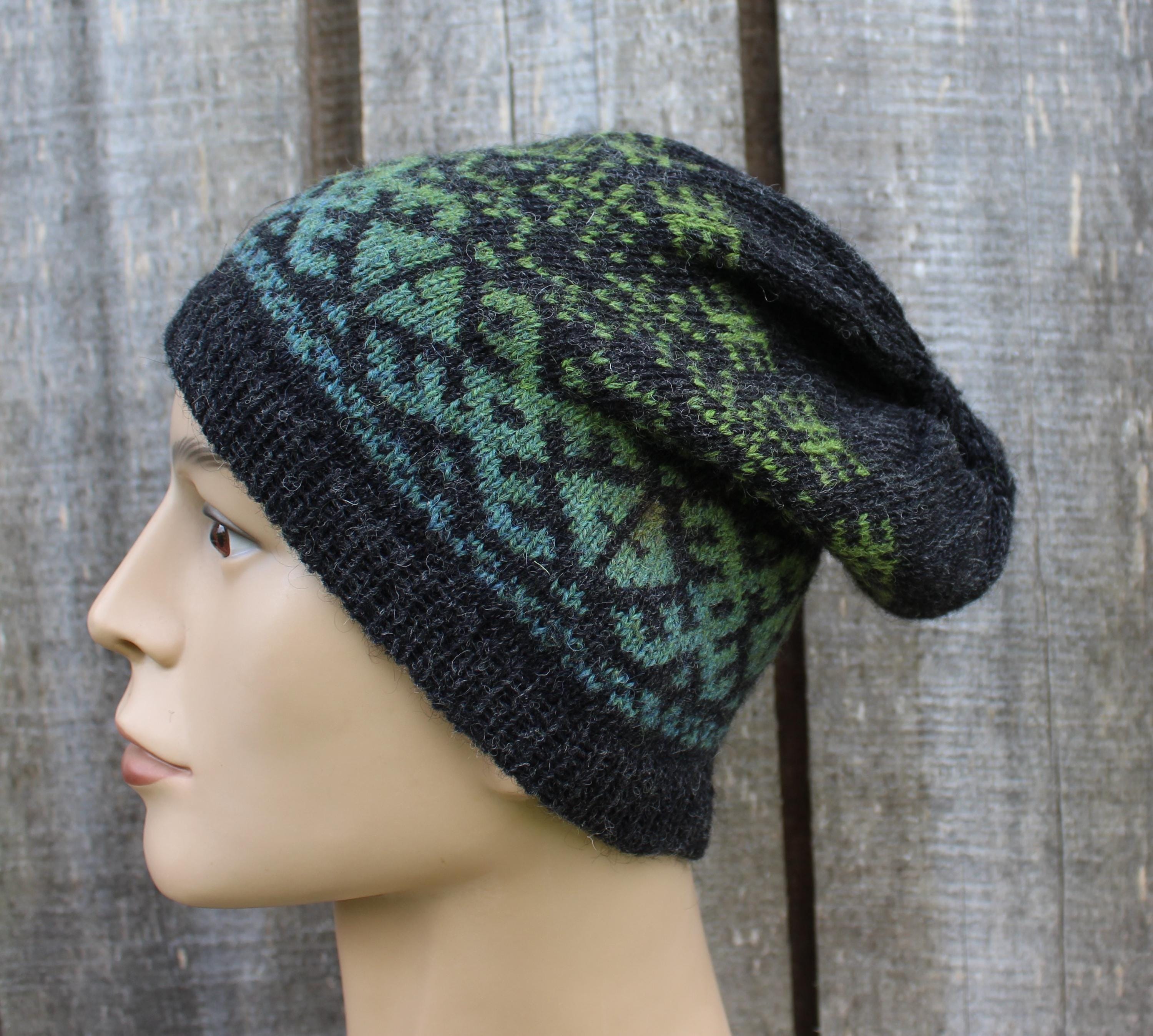 Knitted hat with green and black pattern on a mannequin head against a wooden background