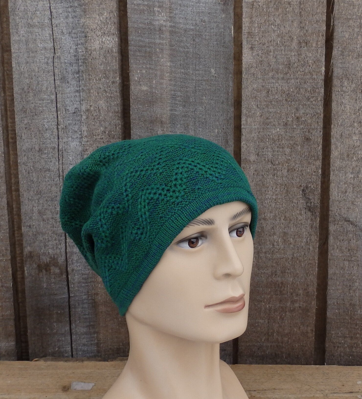 Green knitted beanie on a mannequin head against a wooden background
