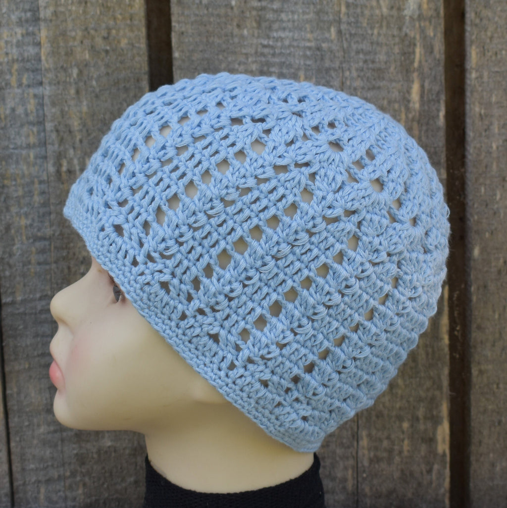 Light blue crochet beanie on a mannequin head against a wooden background