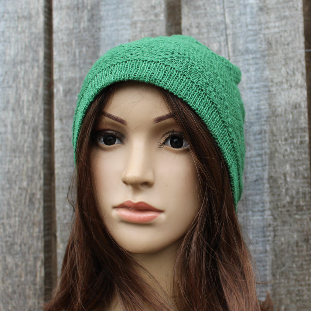 Green knitted beanie on a mannequin head against a wooden background