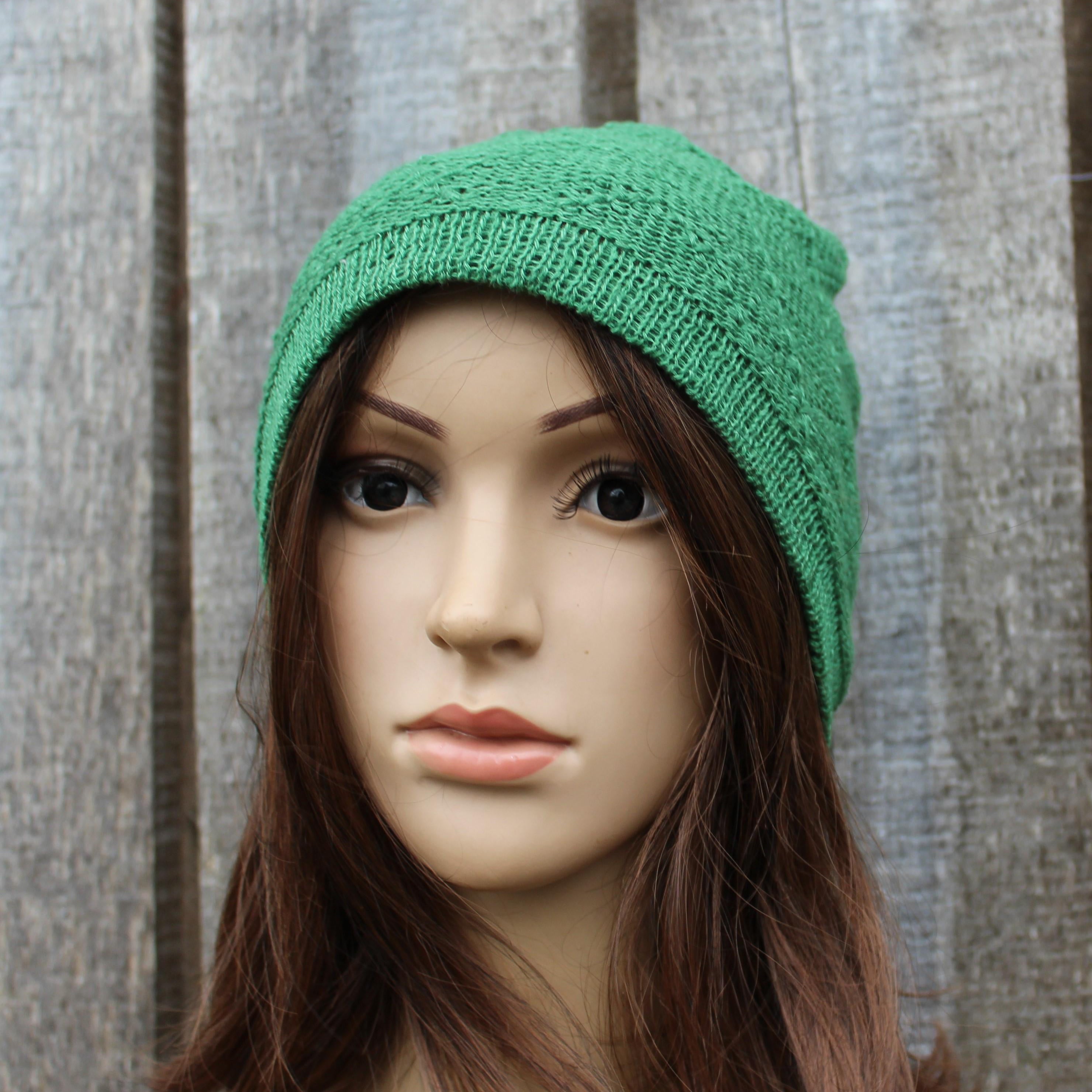 Green knitted beanie on a mannequin head against a wooden background