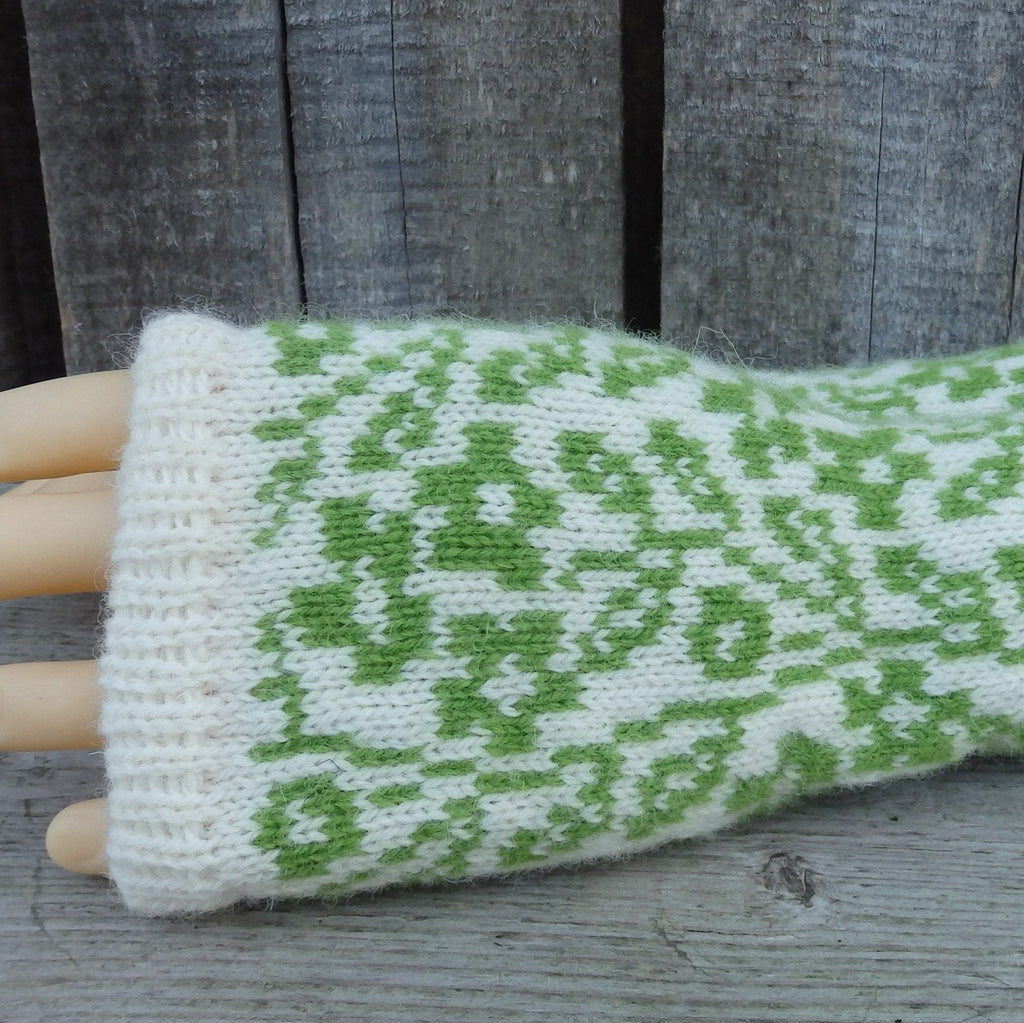Green and white patterned wrist warmer on a mannequin hand against a wooden background