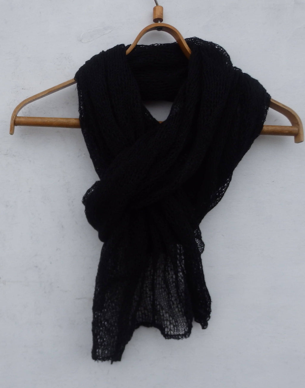 Black scarf on a wooden hanger against a white background