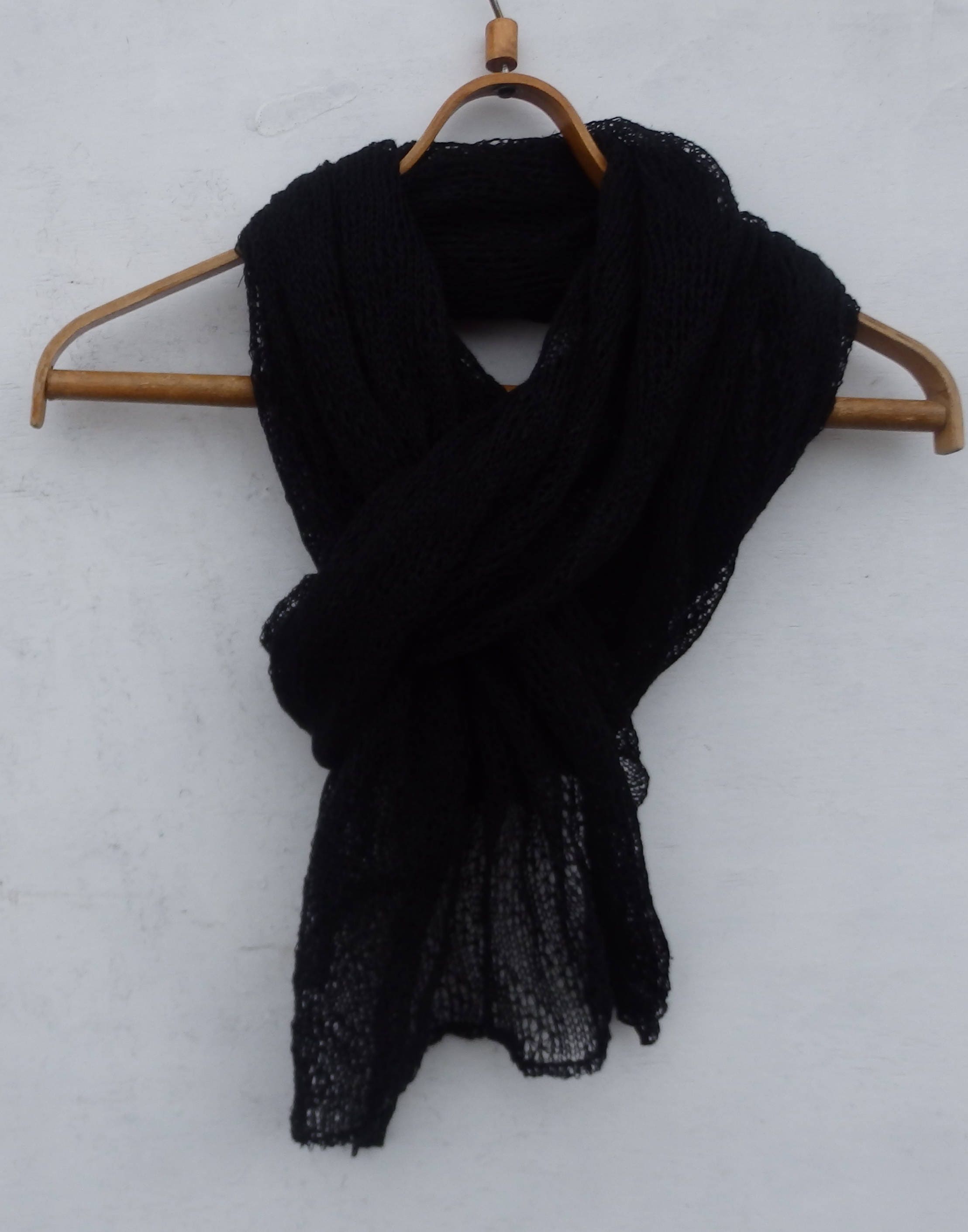 Black scarf on a wooden hanger against a white background