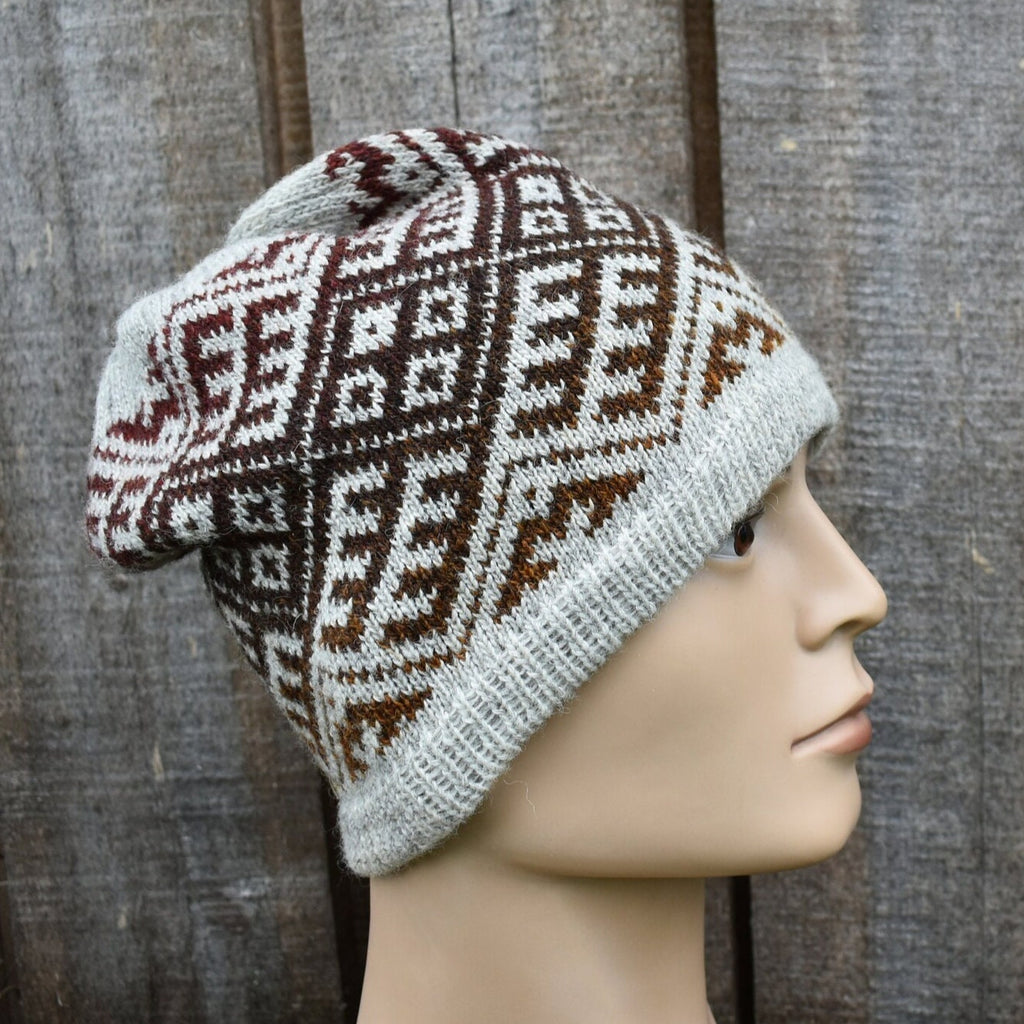 Knitted beanie with a geometric pattern on a mannequin head against a wooden background