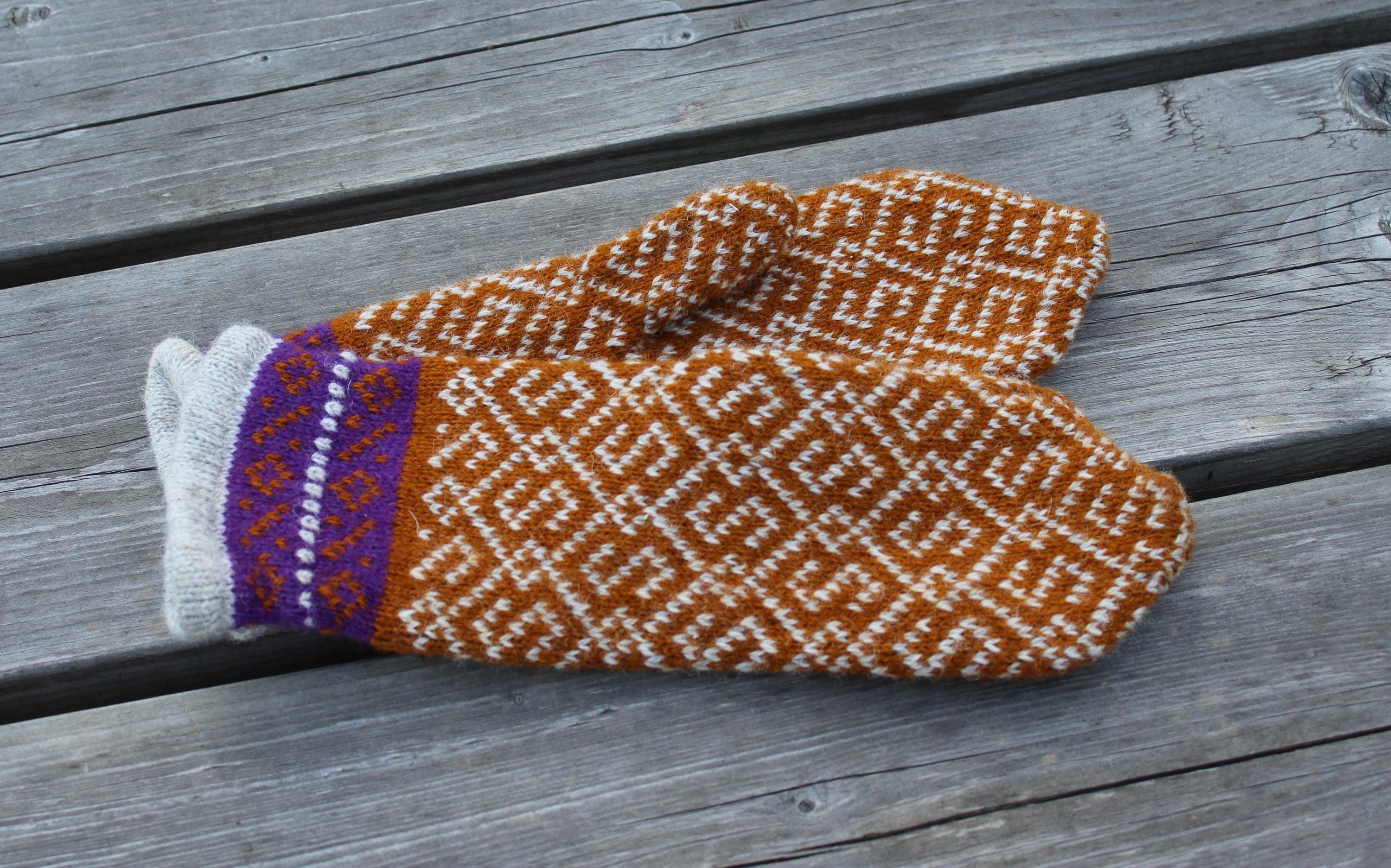 Pair of knitted mittens with a geometric pattern on a wooden surface