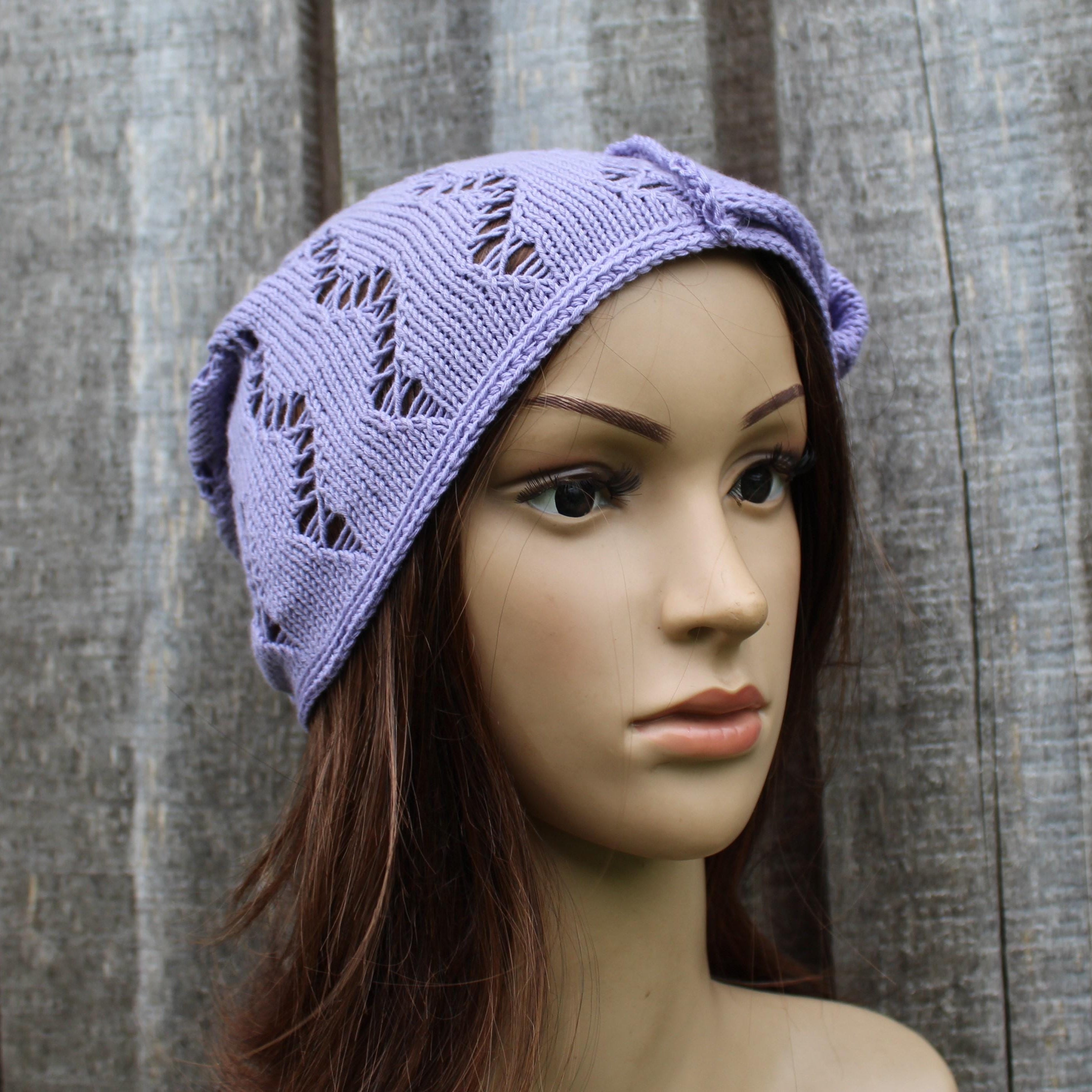 Mannequin head wearing a purple knitted hat against a wooden background