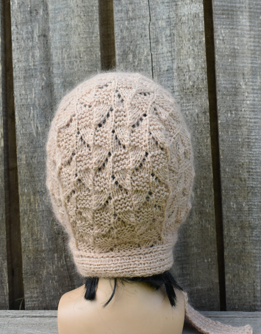 Knitted hat on a mannequin head against a wooden background
