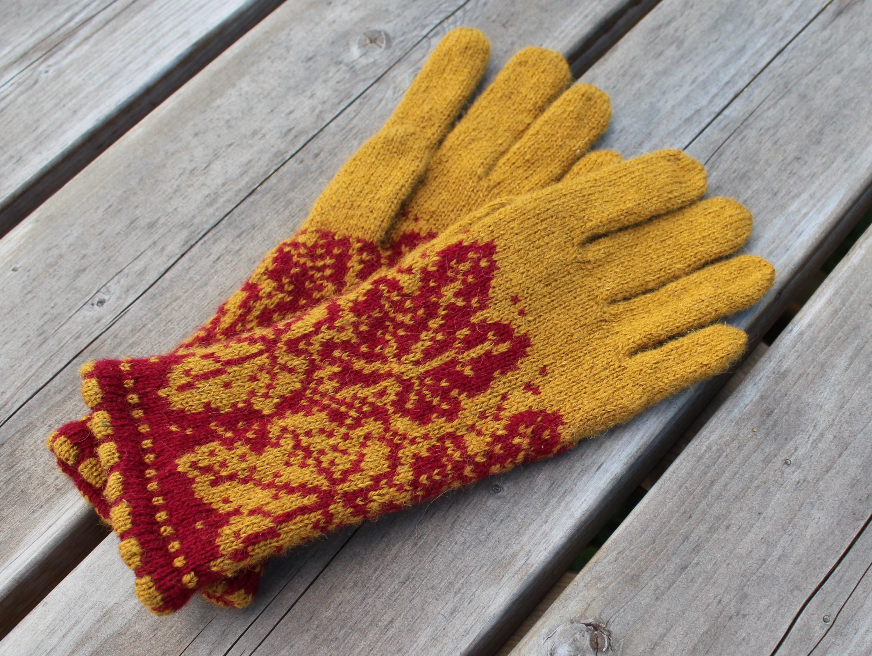 Pair of yellow and red patterned gloves on a wooden surface