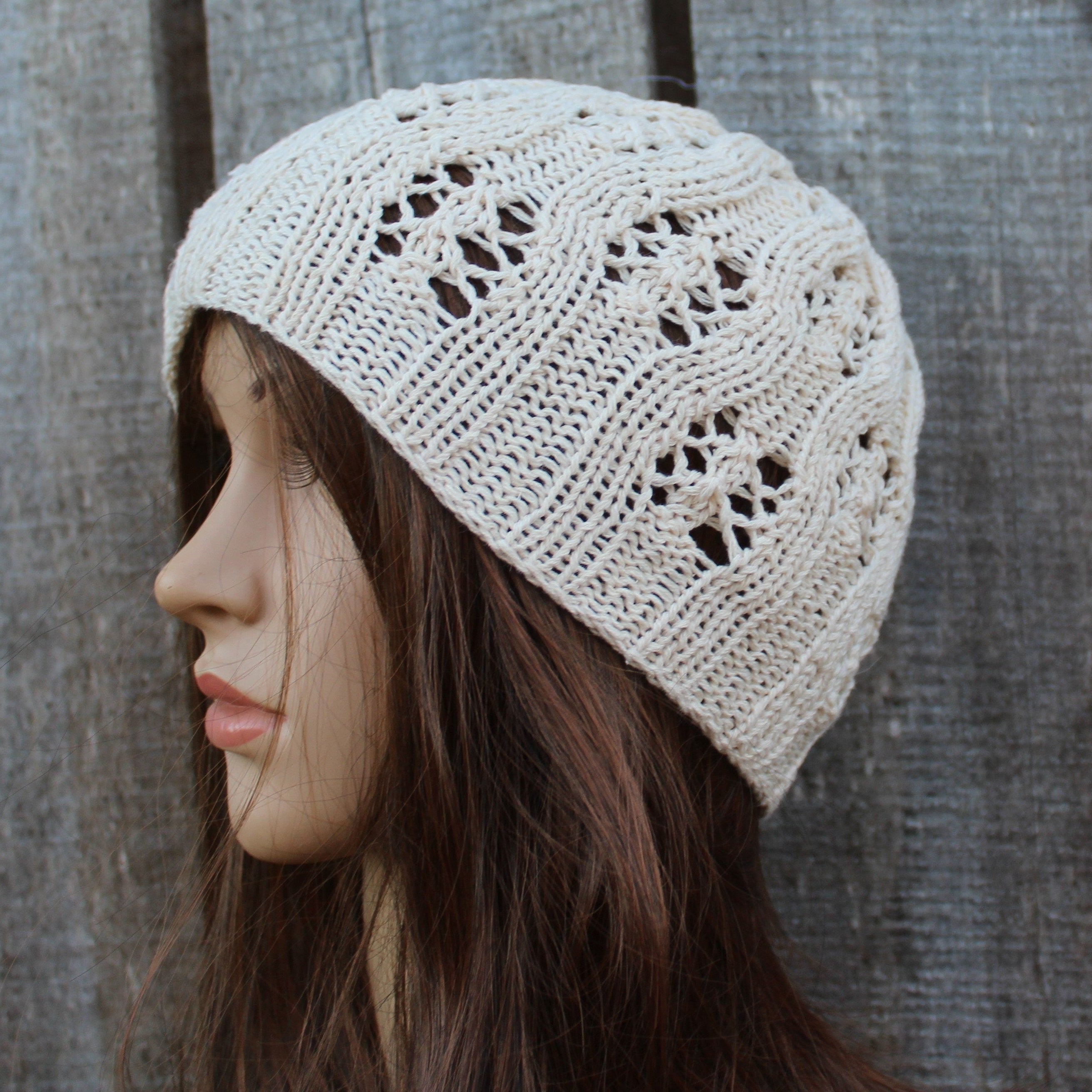 Woman wearing a beige knitted hat against a wooden background
