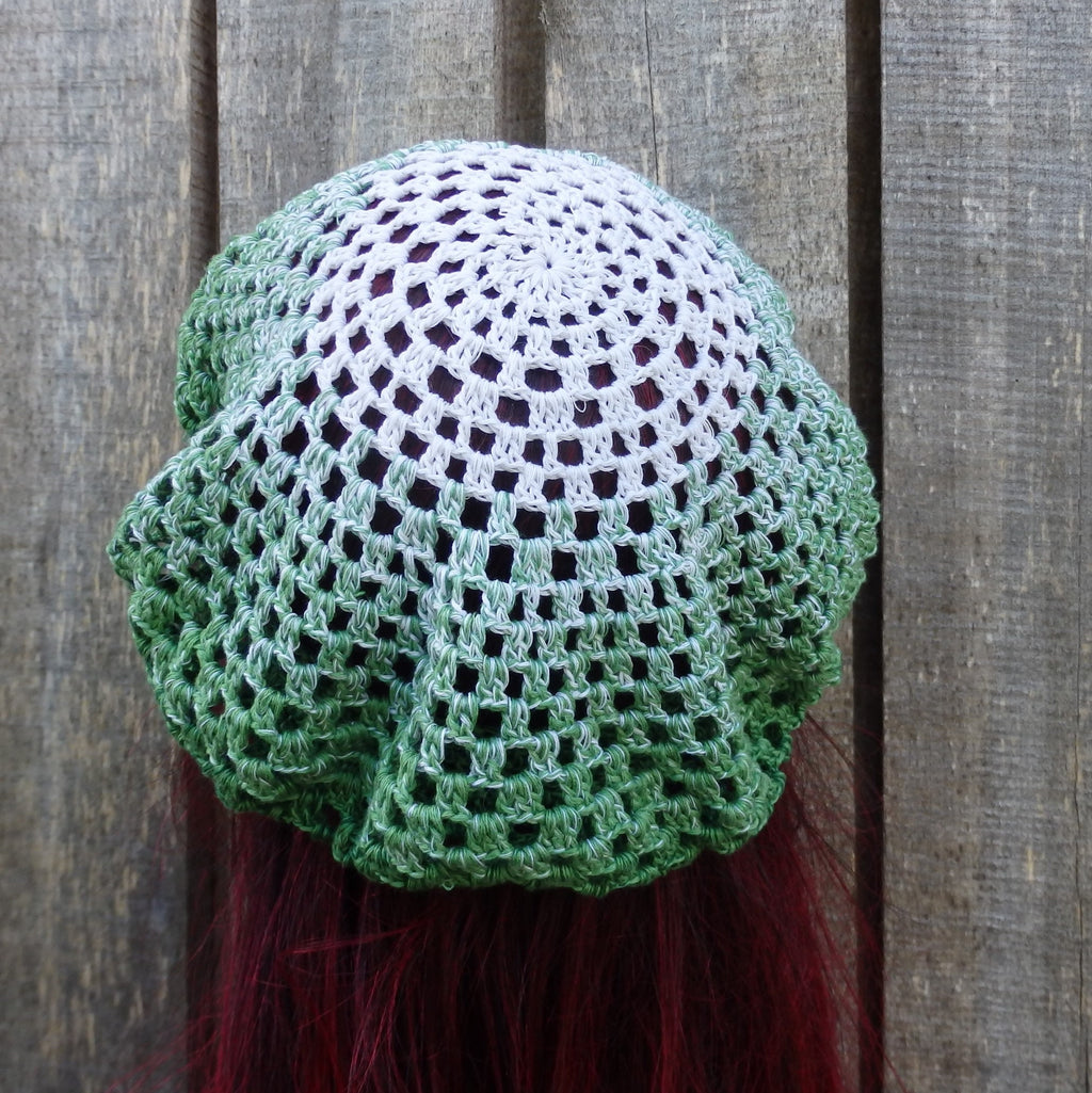 Green and white crocheted headscarf on a wooden background