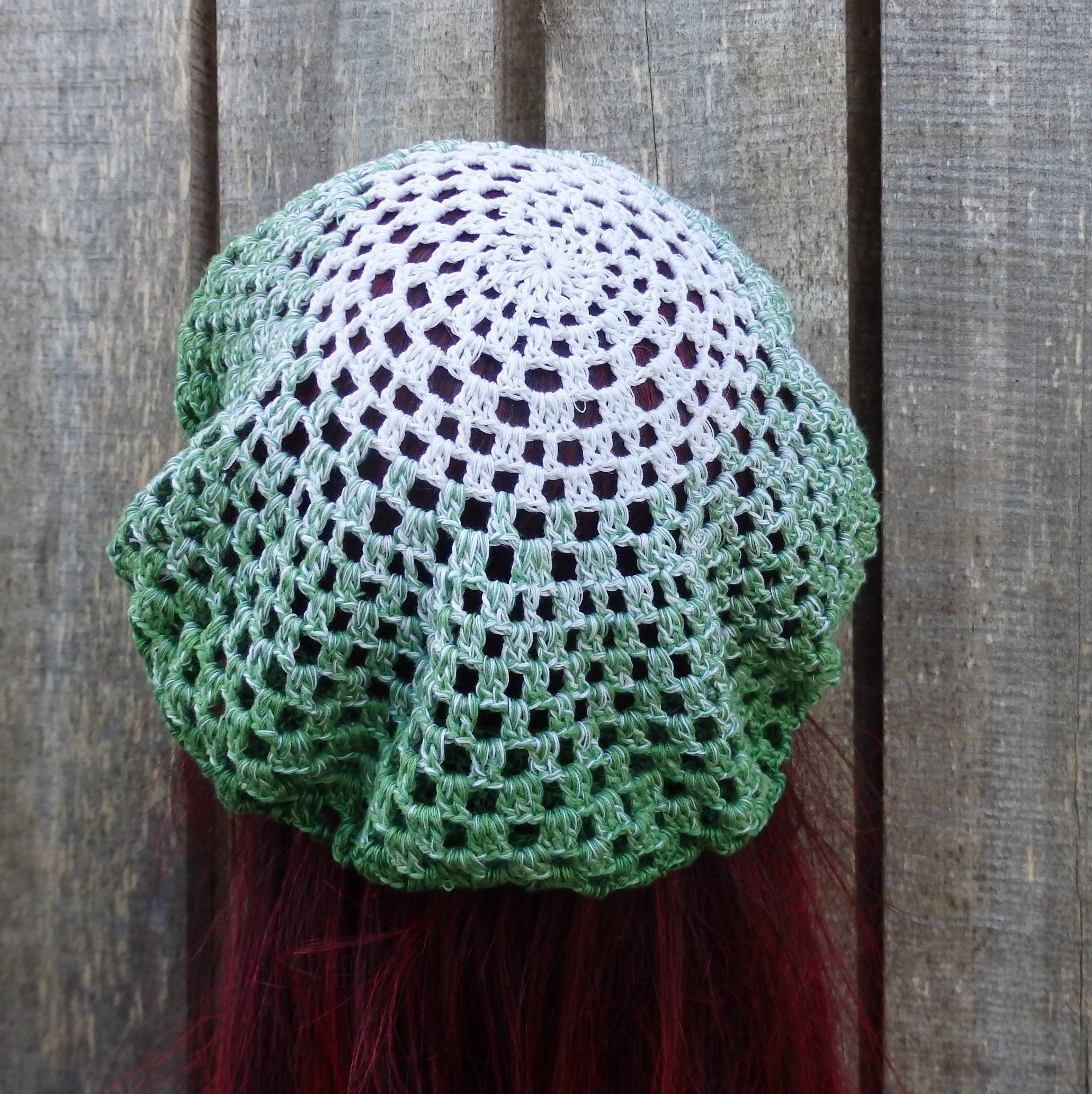 Green and white crocheted headscarf on a wooden background