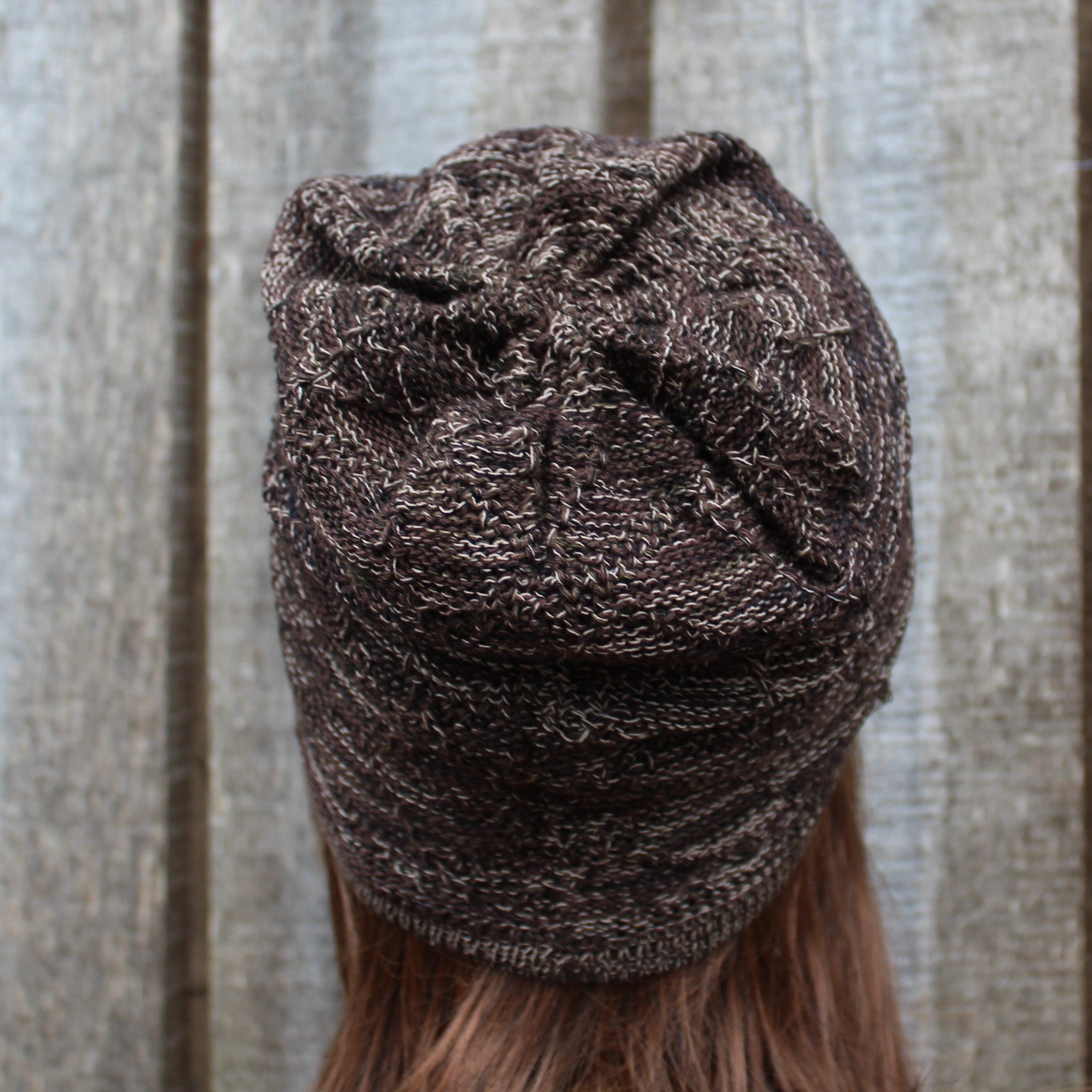 Brown knit beanie worn by a person against a wooden panel background