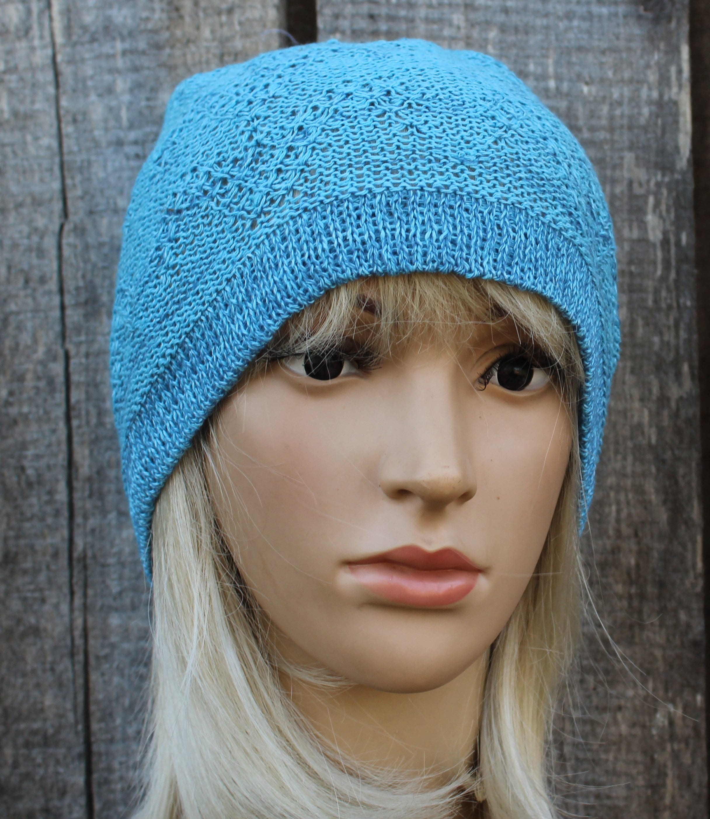 Blue knitted beanie on a mannequin head against a wooden background
