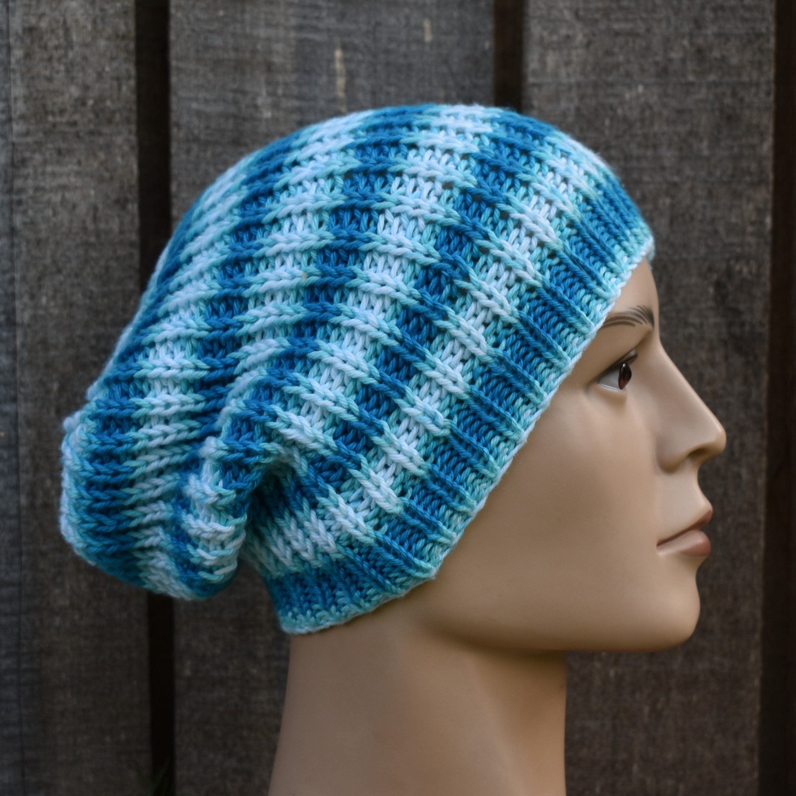 Blue and white striped knitted hat on a mannequin head against a wooden background