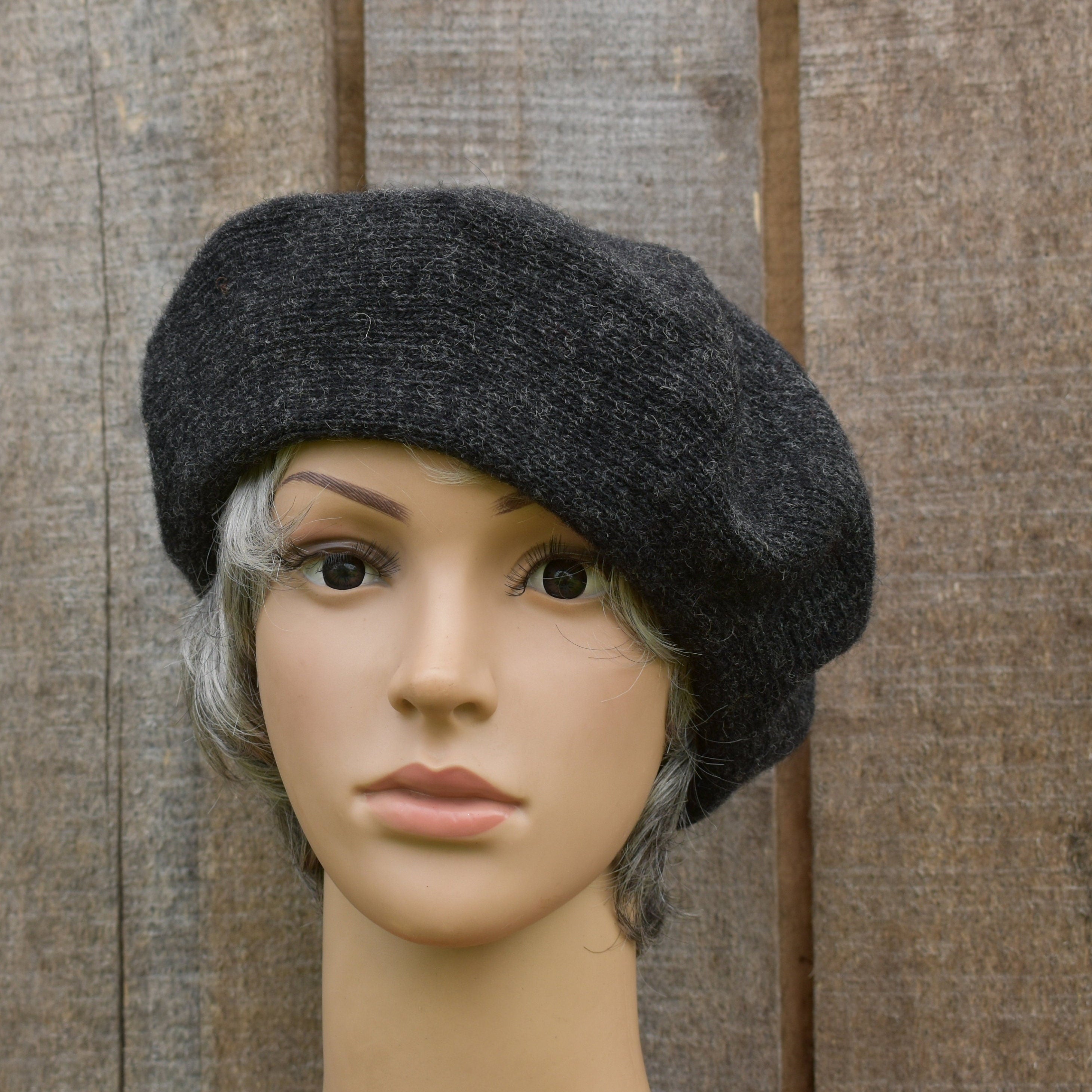 Dark gray beret on a mannequin head against a wooden background