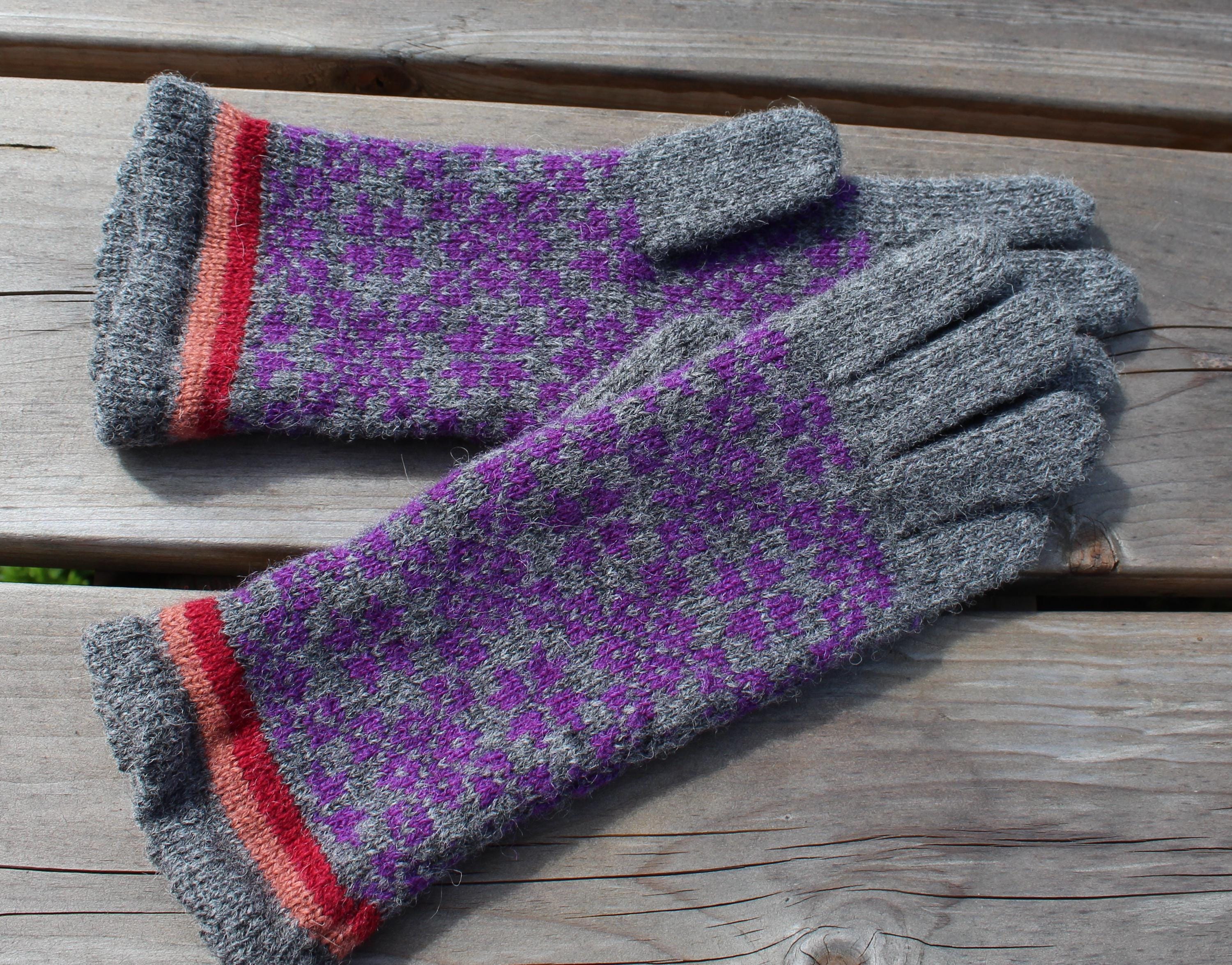 Pair of gloves with purple pattern and gray cuffs on a wooden surface