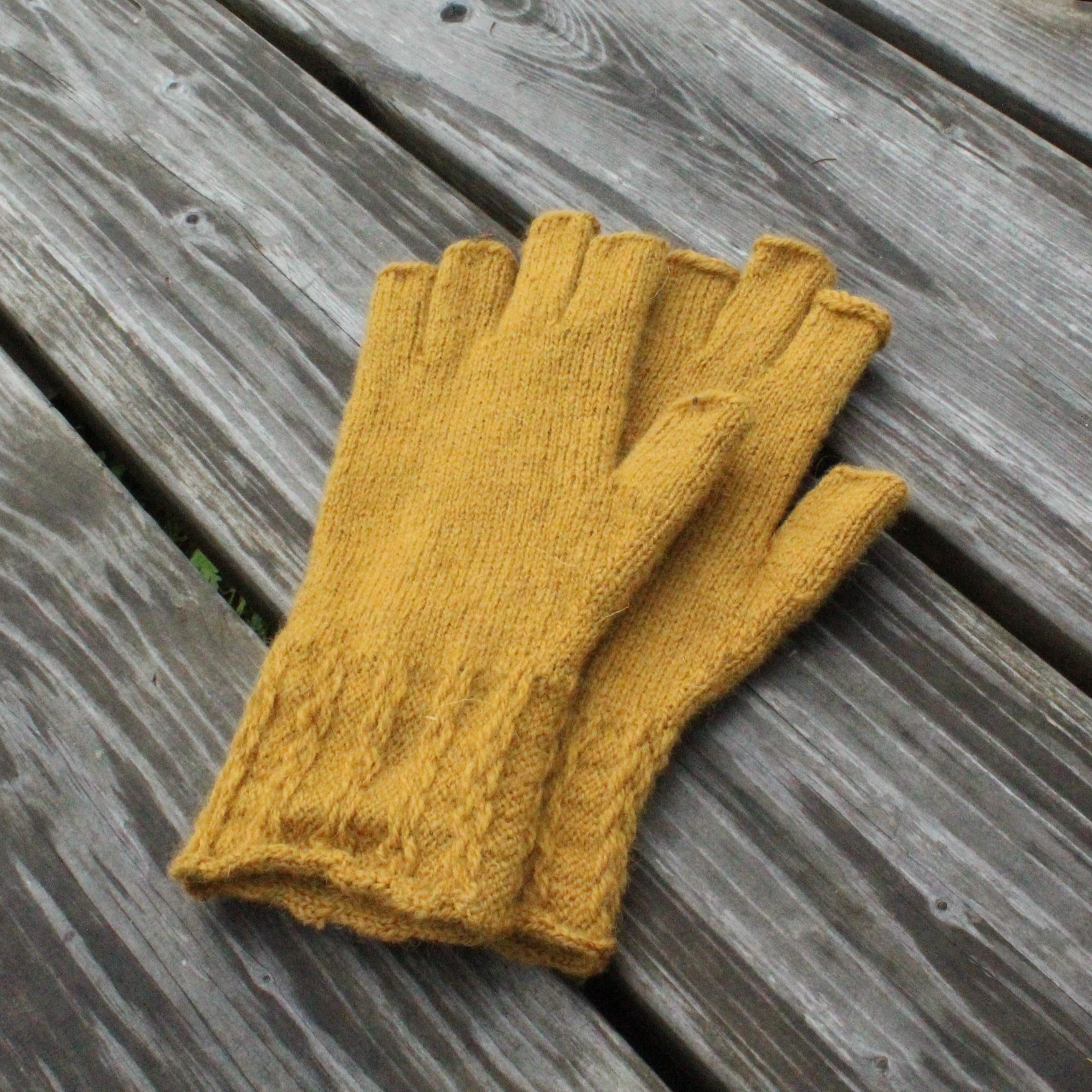 Pair of mustard yellow gloves on a wooden surface
